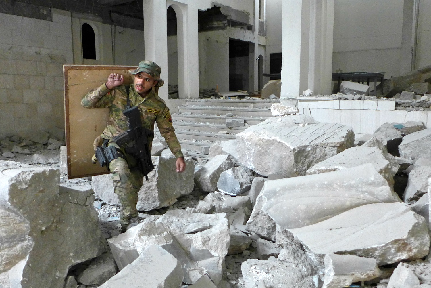 Iraqi Special Forces soldier rescues a paintng, one of only two items left undamaged in Mosul Museum in 2017 (Tom Westcott/MEE)