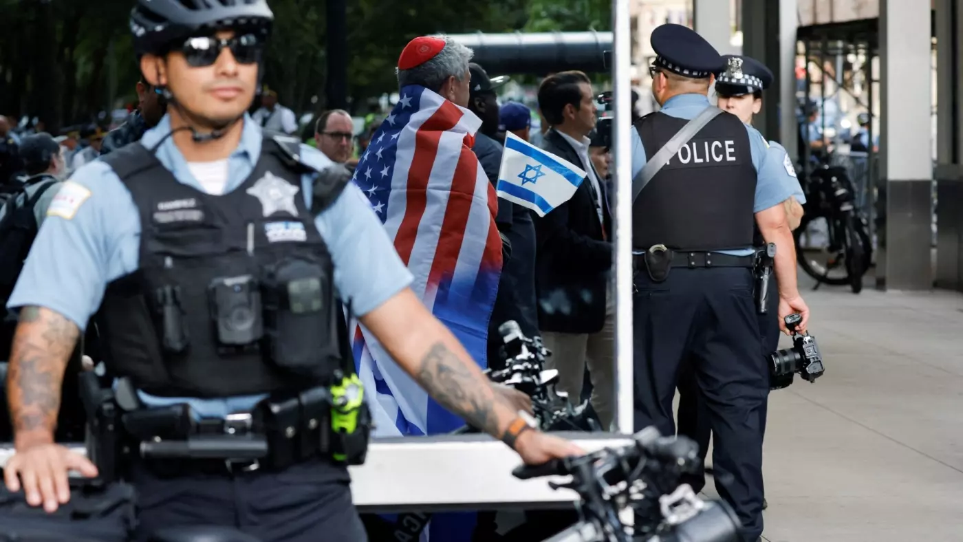 Police officers stand guard as a man carrying an Israeli flag and an American flag looks on while other demonstrators protest in support of Palestinians, near Israeli consulate in Chicago, Illinois, on 20 August 2024 (Eduardo Munoz/Reuters)