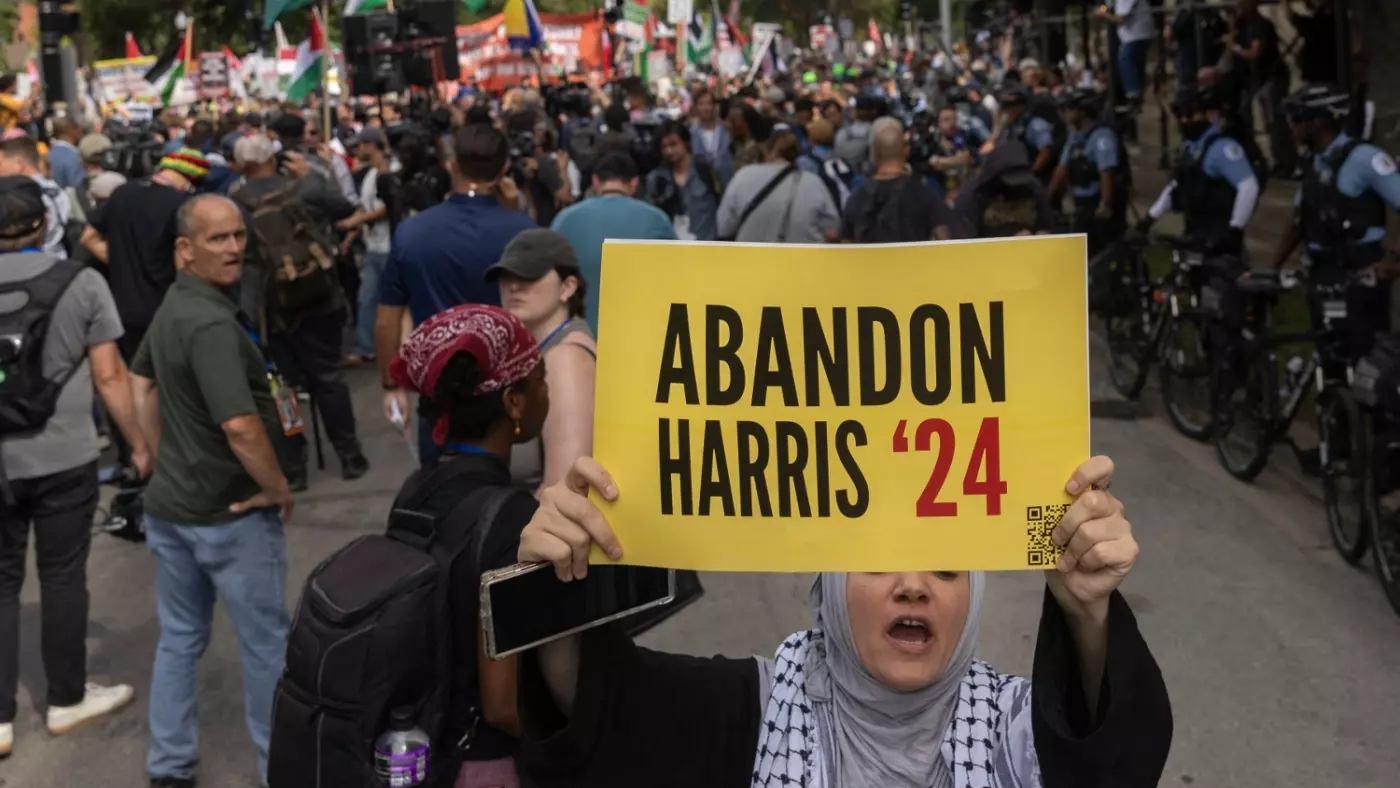 A protester holds a sign reading 'Abandon Harris' as she marches with others at Democratic National Convention before the start of event in Chicago, Illinois, on 19 August 2024 (Christian Monterrosa/AFP)