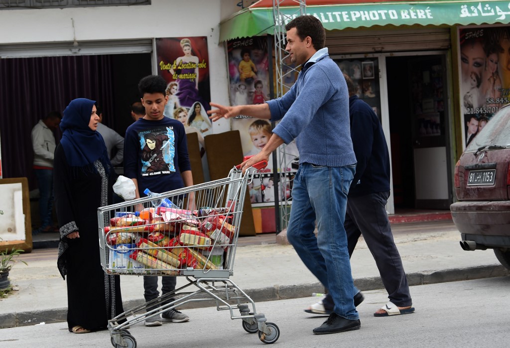 A man pushes a shopping trolley along a street in Ettadhamen on 30 April 2018 (AFP)