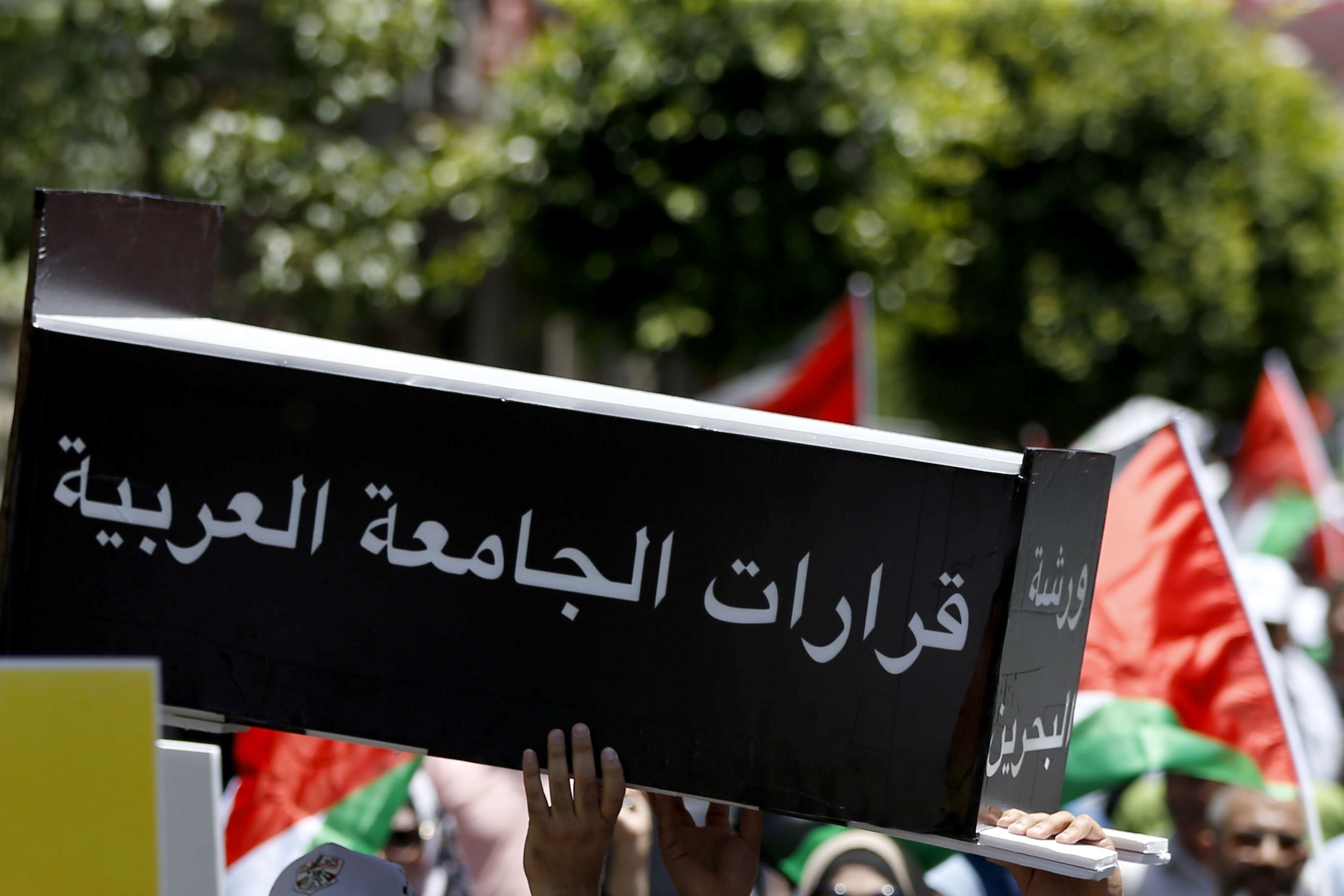 Palestinian demonstrators carry a makeshift coffin with the inscription 