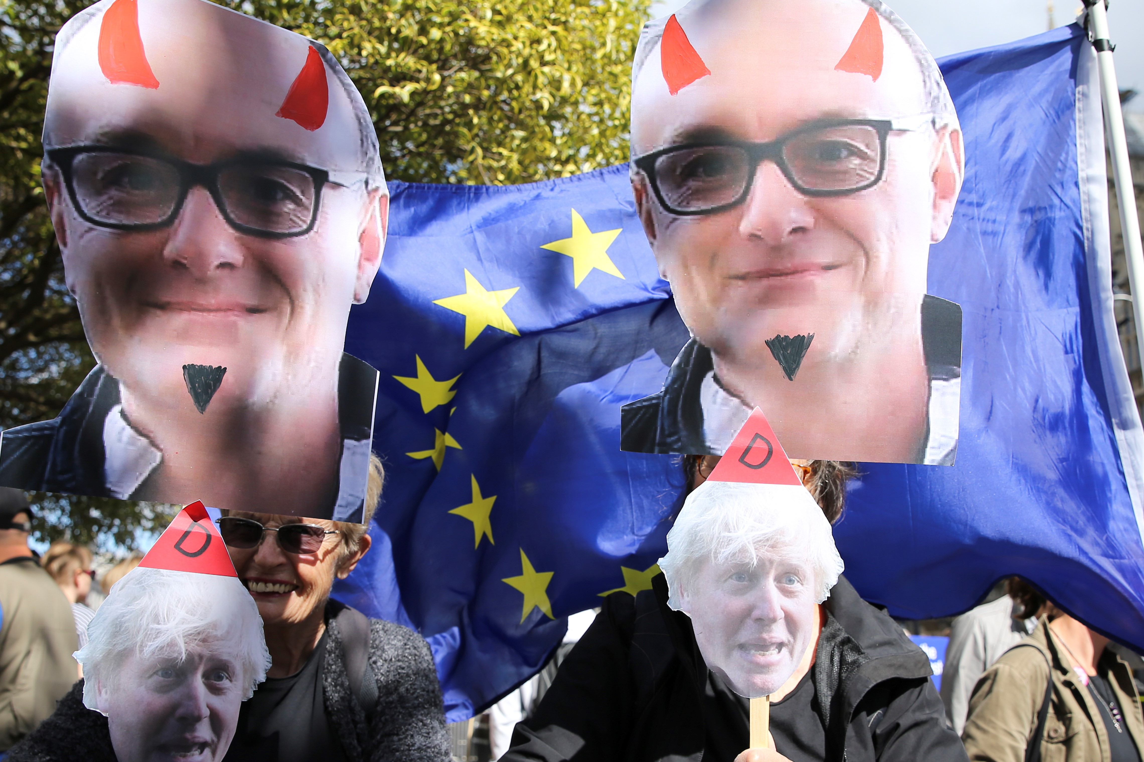   Anti-Brexit activists holding placards showing the faces of Britain's Prime Minister Boris Johnson and his chief adviser Dominic Cummings outside the Houses of Parliament on 4 September, 2019 (AFP)