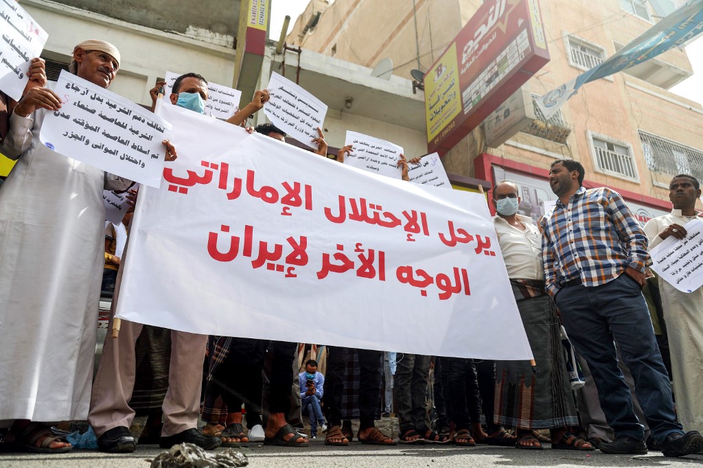 Yemenis hold up a large sign reading in Arabic 