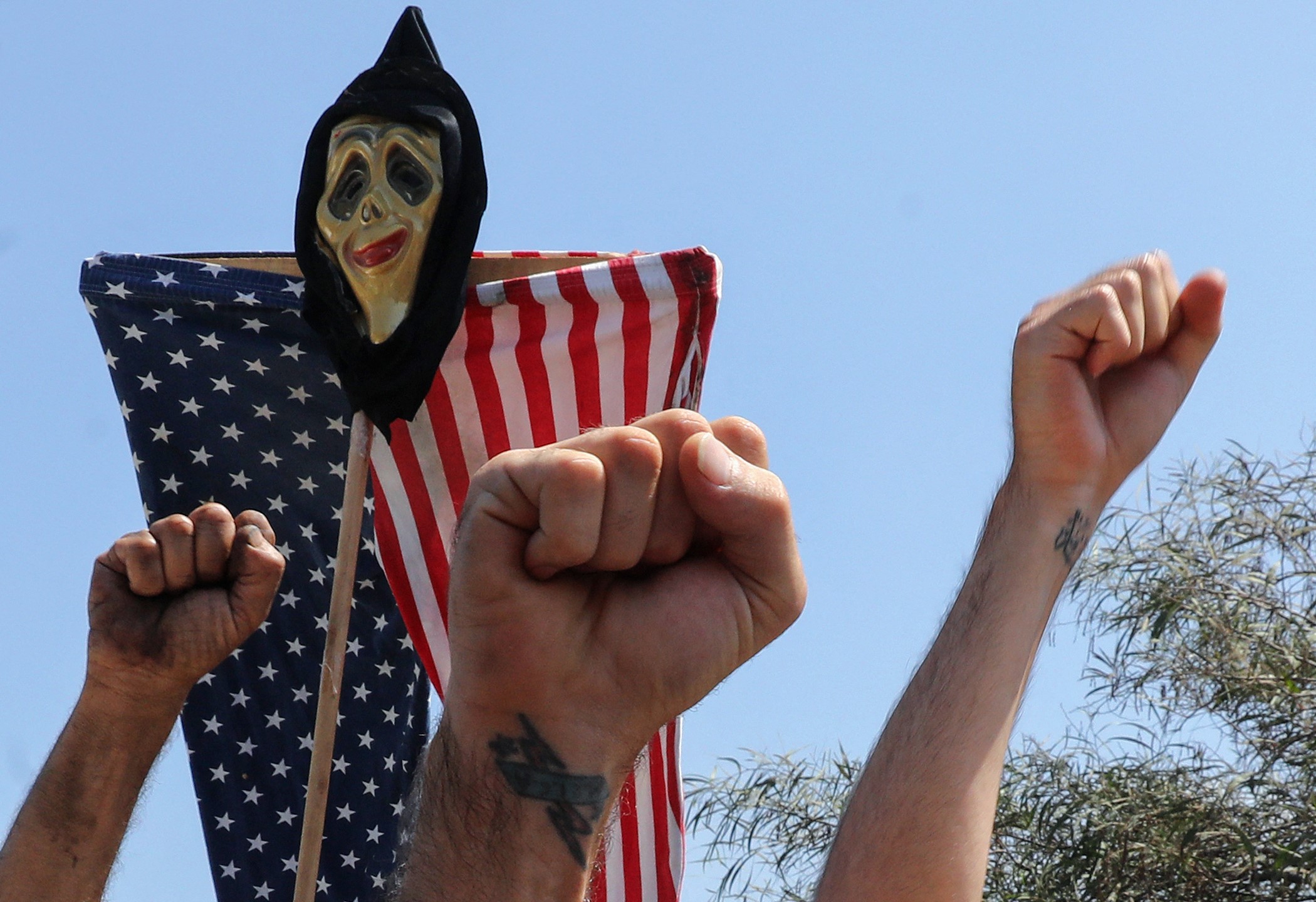 Lebanese supporters of Hezbollah and the Communist Party raise clenched fists beneath an anti-US effigy, during a protest at the entrance of Beirut's international airport on 8 July, 2020 (AFP)