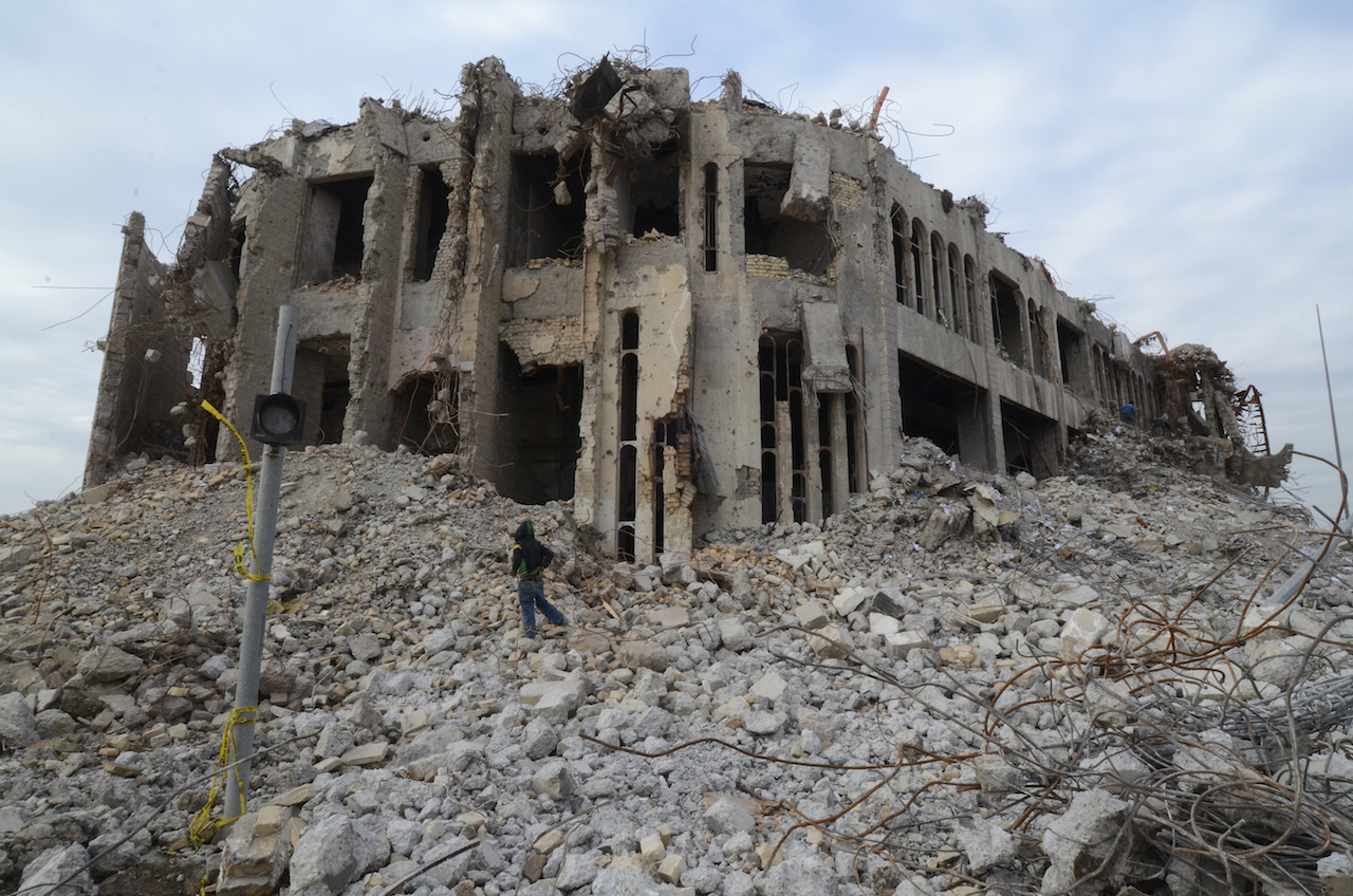 An Iraqi climbs up the rubble of the destroyed seven-storey National Insurance Company Building, designed by celebrated Iraqi architect Rifat Chadirji (AFP)