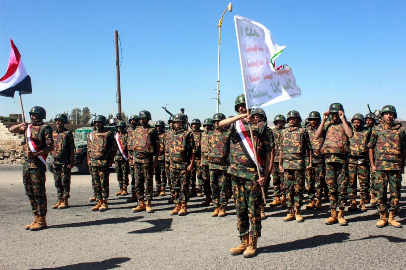 Des combattants houthis défilent après avoir obtenu leur diplôme, à Saada, en mars 2019. Le slogan houthi est inscrit sur l’étendard (AFP)