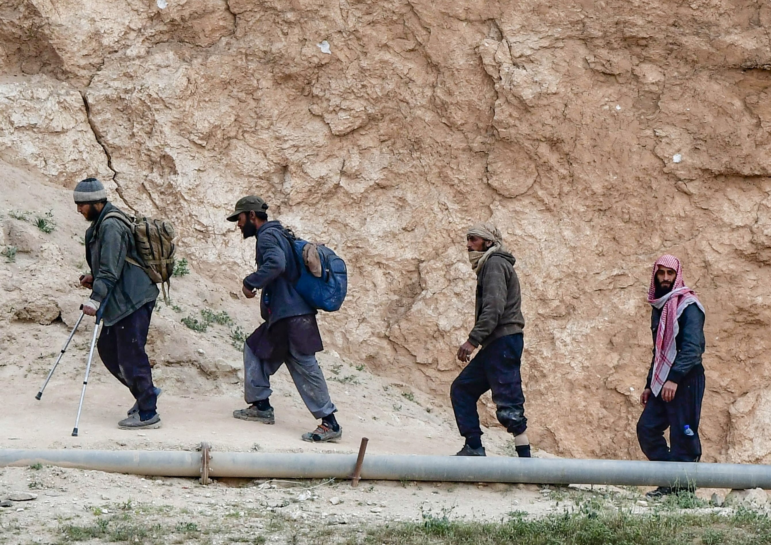  People said to be members of IS by the US-backed Syrian Democratic Forces (SDF), exit from the village of Baghouz in the eastern Syrian province of Deir Ezzor, on 14 March (AFP)