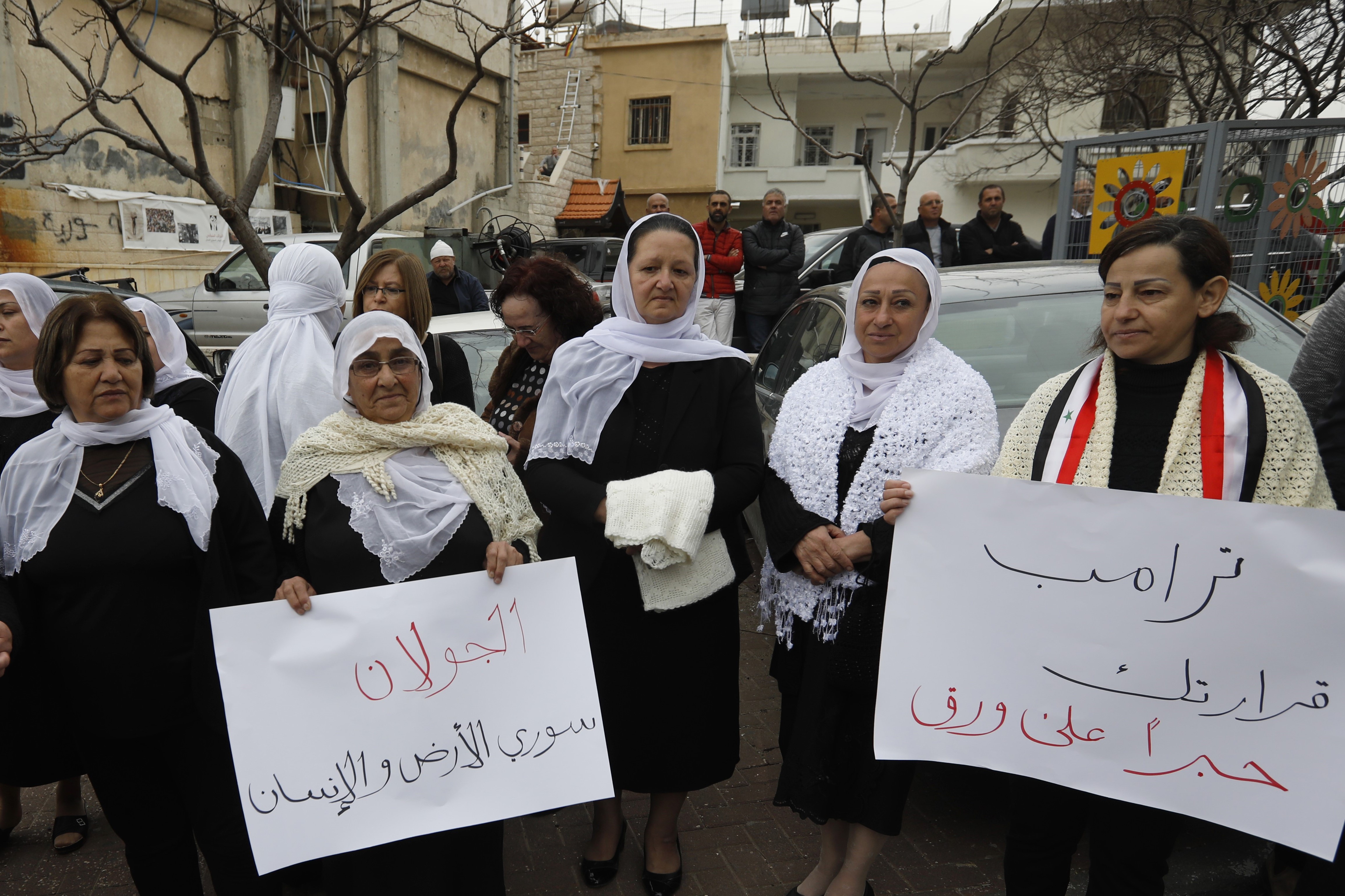 Residents of the Golan Heights raise Syrian banners during a protest against the backing of Israel's capture of the Golan Heights by the US president, on 23 March (AFP)