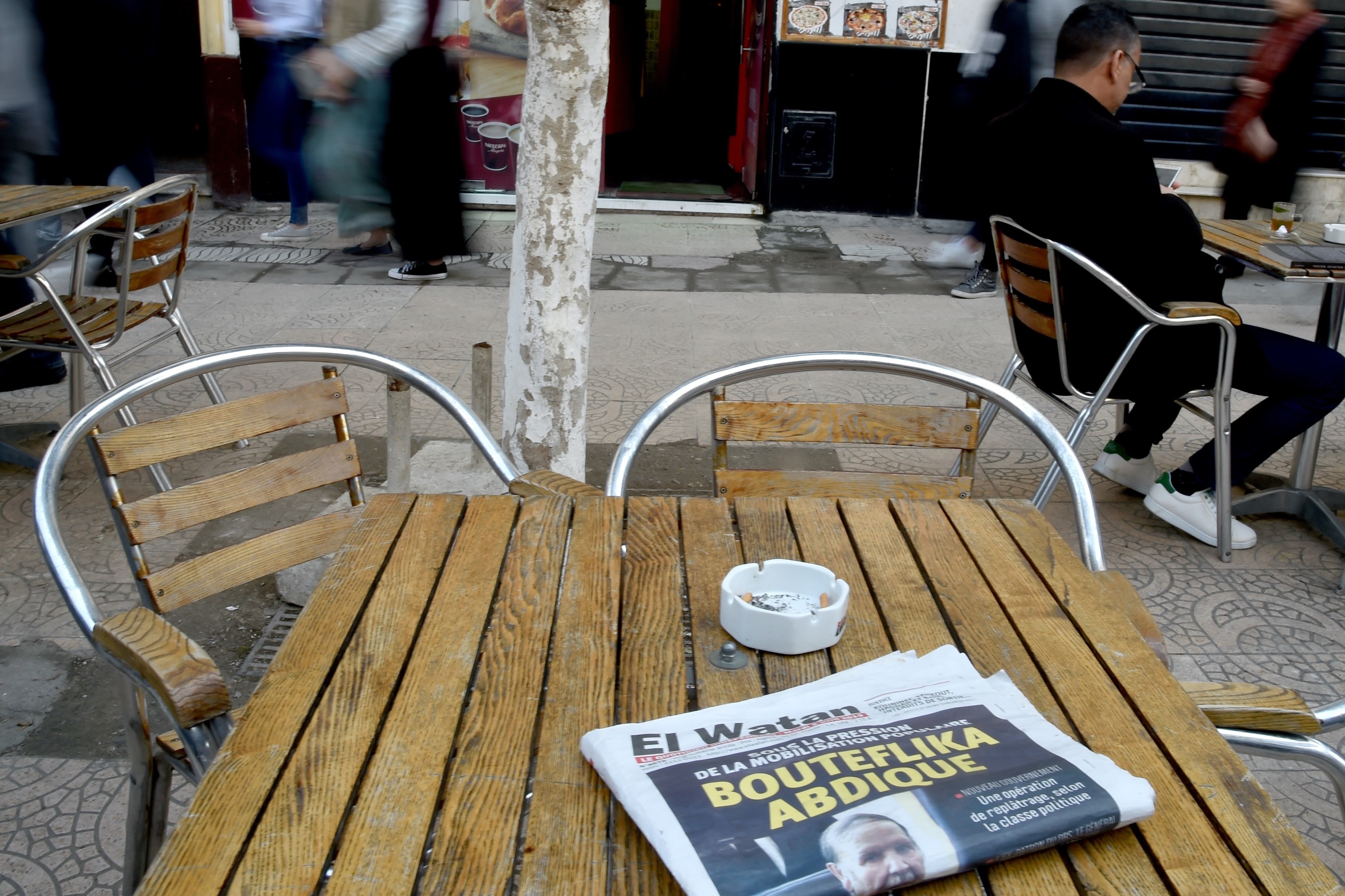 Algerians walk past a newspaper reading 