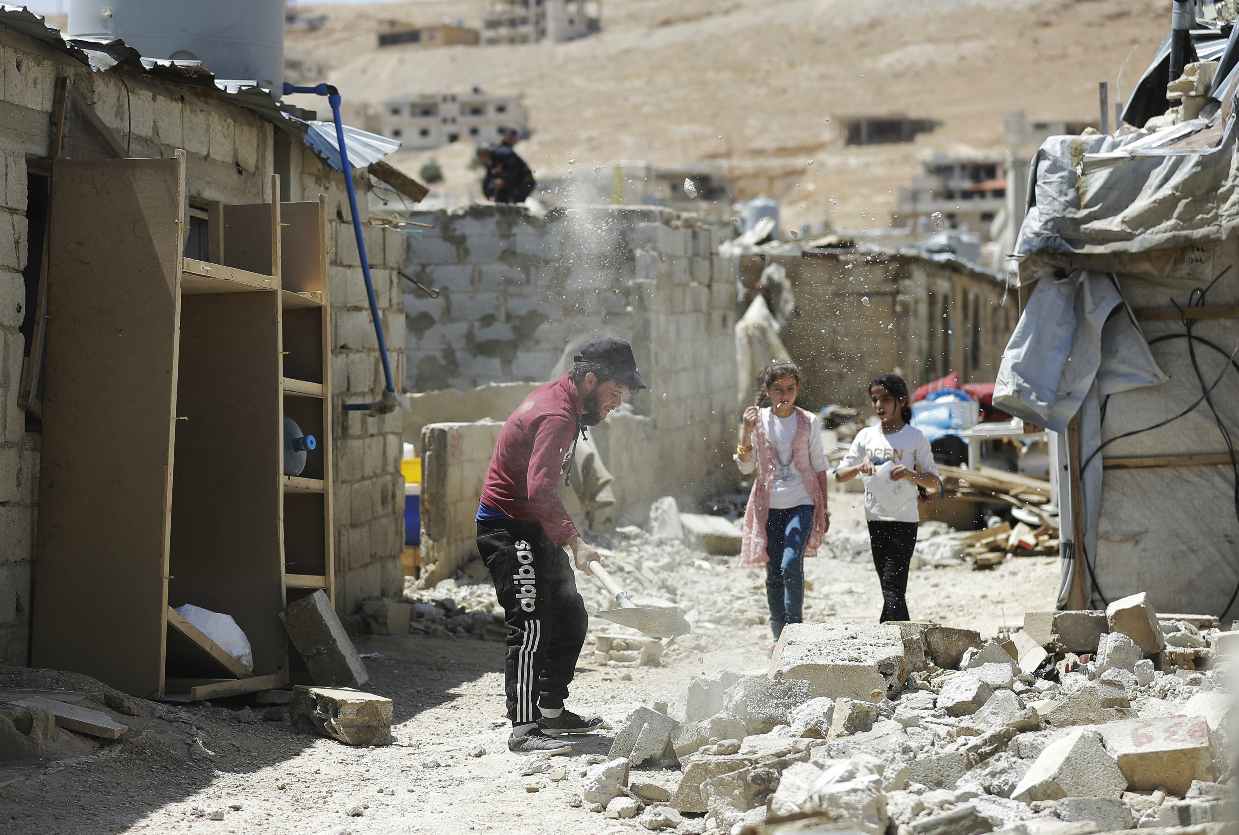 Two girls walking past a demolished schack in a refugee housing in the northeastern Lebanese town of Arsal, in the Bekaa valley (AFP)