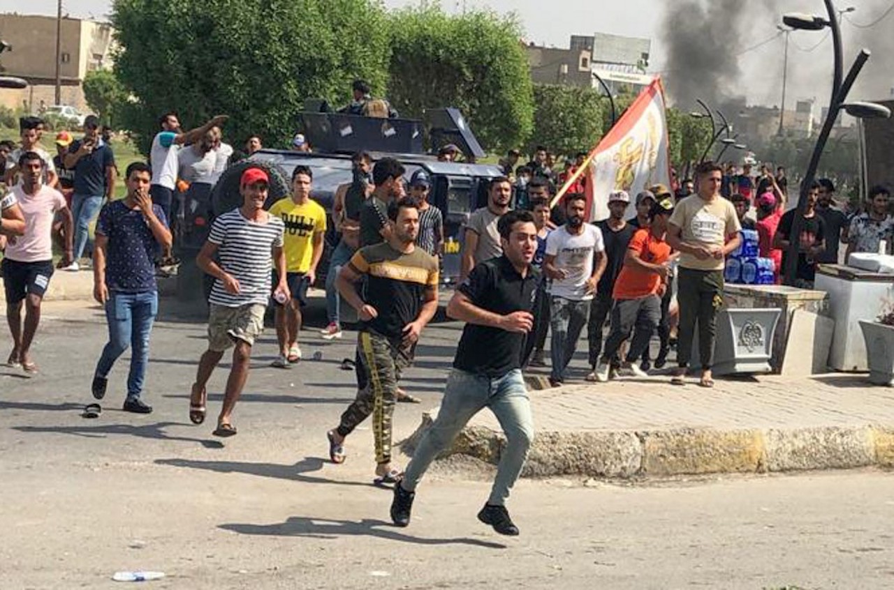 Iraqi protesters run during a demonstration against corruption and lack of basic services in Baghdad's al-Zaafaraniya district (AFP)