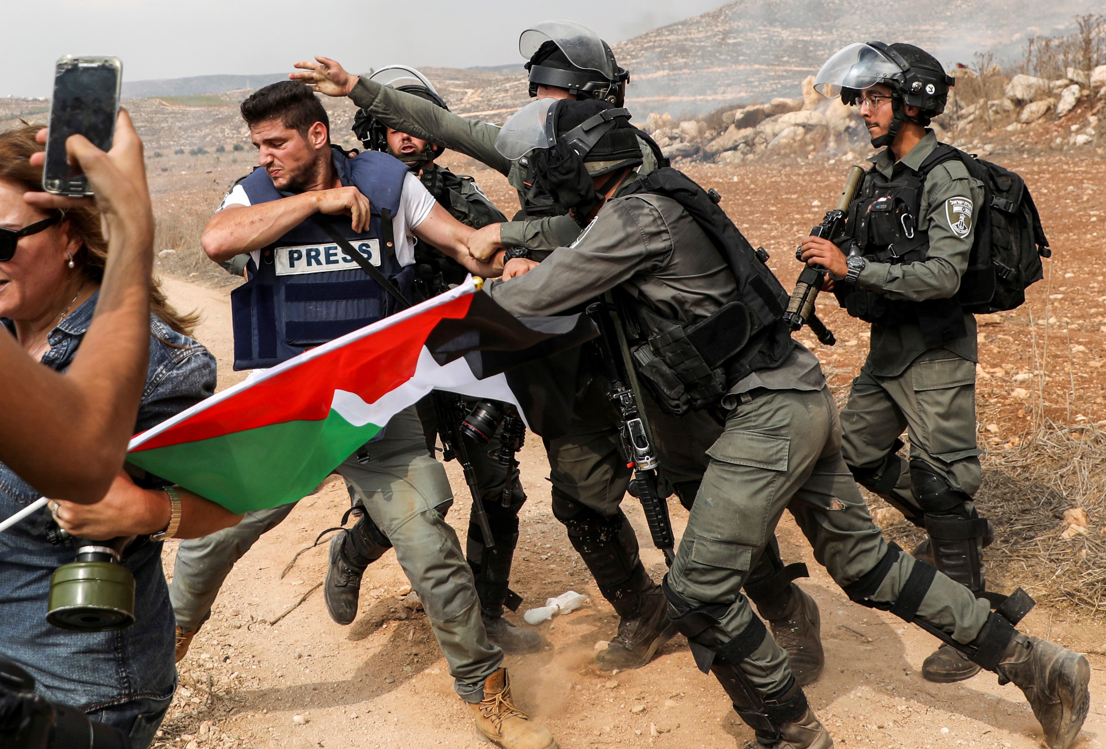 Israeli soldiers stand by as masked settlers throw stones towards Palestinian protesters, north of Ramallah in the occupied West Bank, on 17 October (AFP)