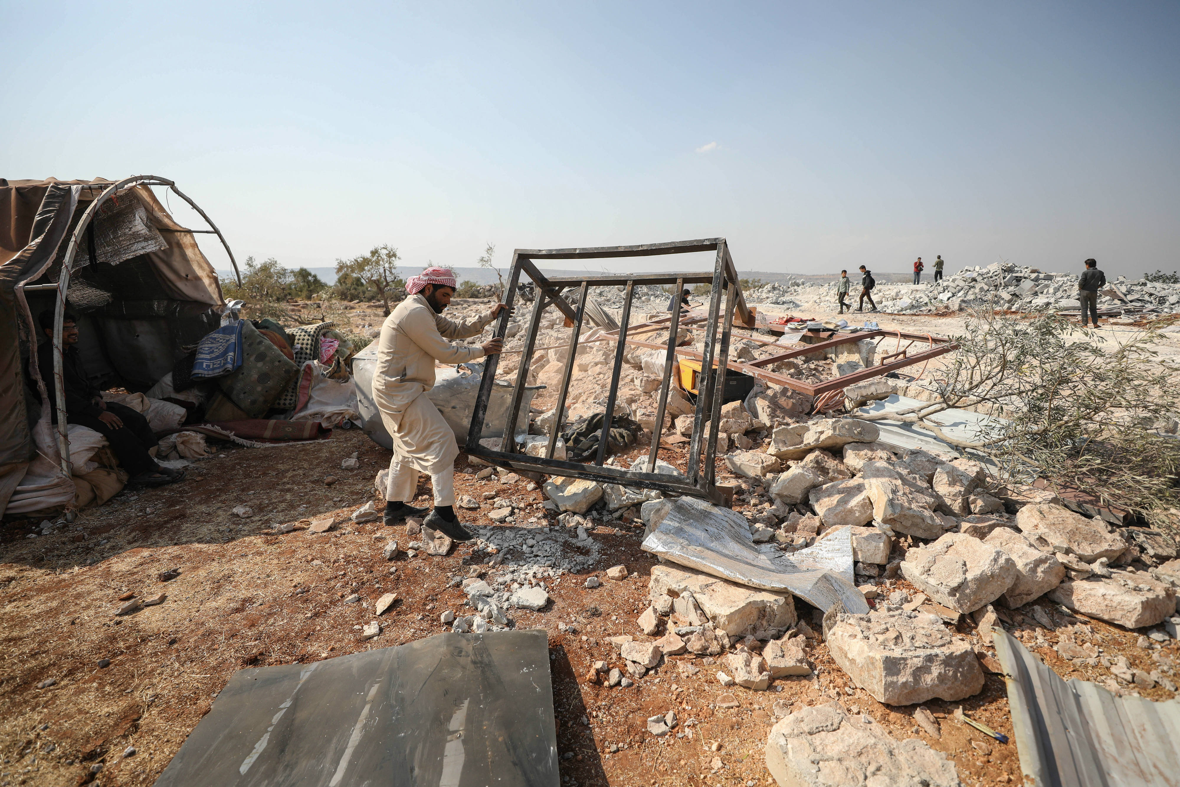 A Syrian man clears debris at the site of the US raid near the northwestern Syrian village of Barisha in the Idlib province along the border with Turkey (AFP)