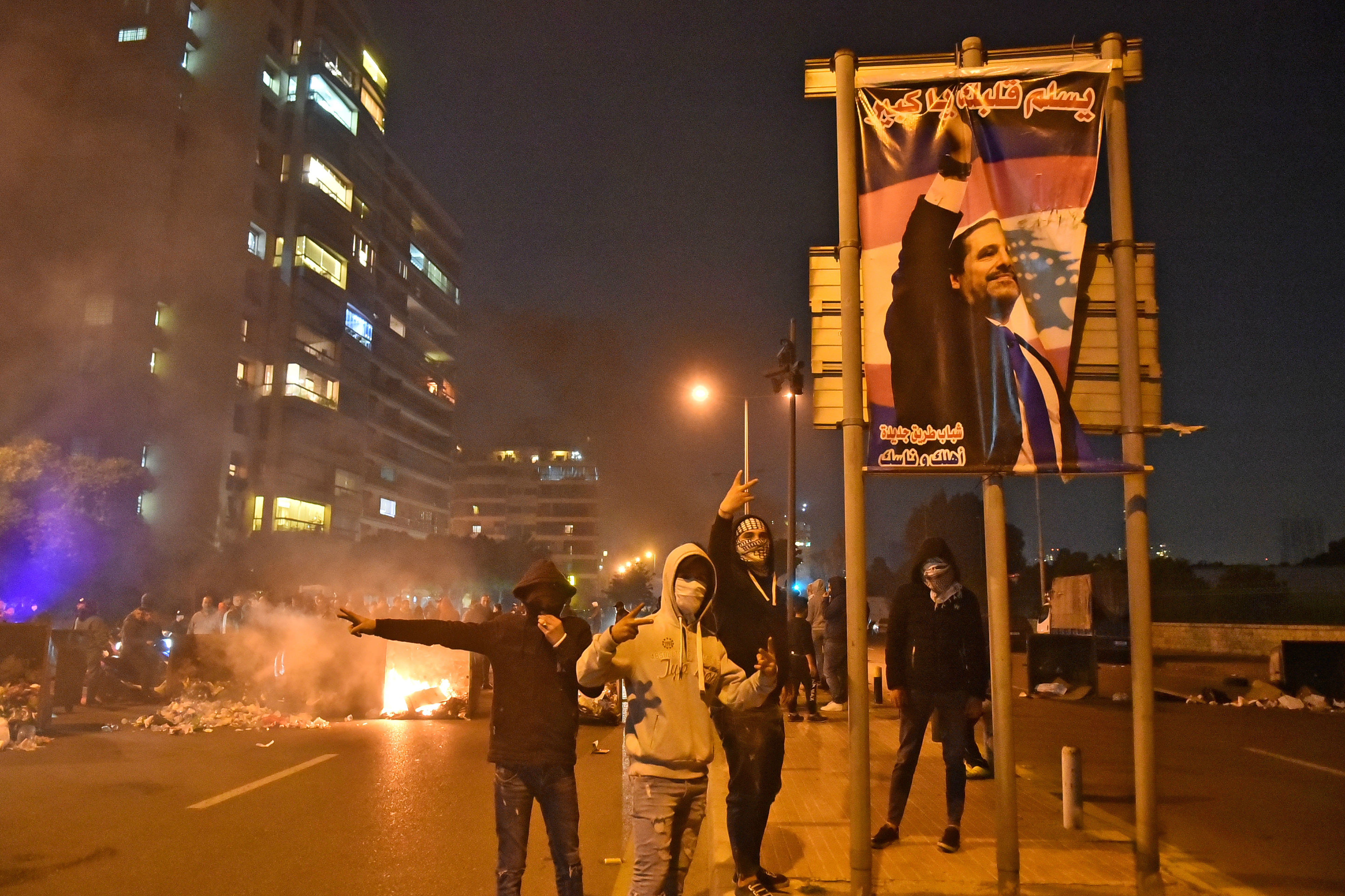 Des partisans du Premier ministre sortant Saad Hariri près d’une affiche le représentant alors qu’ils bloquent une route dans le quartier de Qasqas à Beyrouth (AFP)