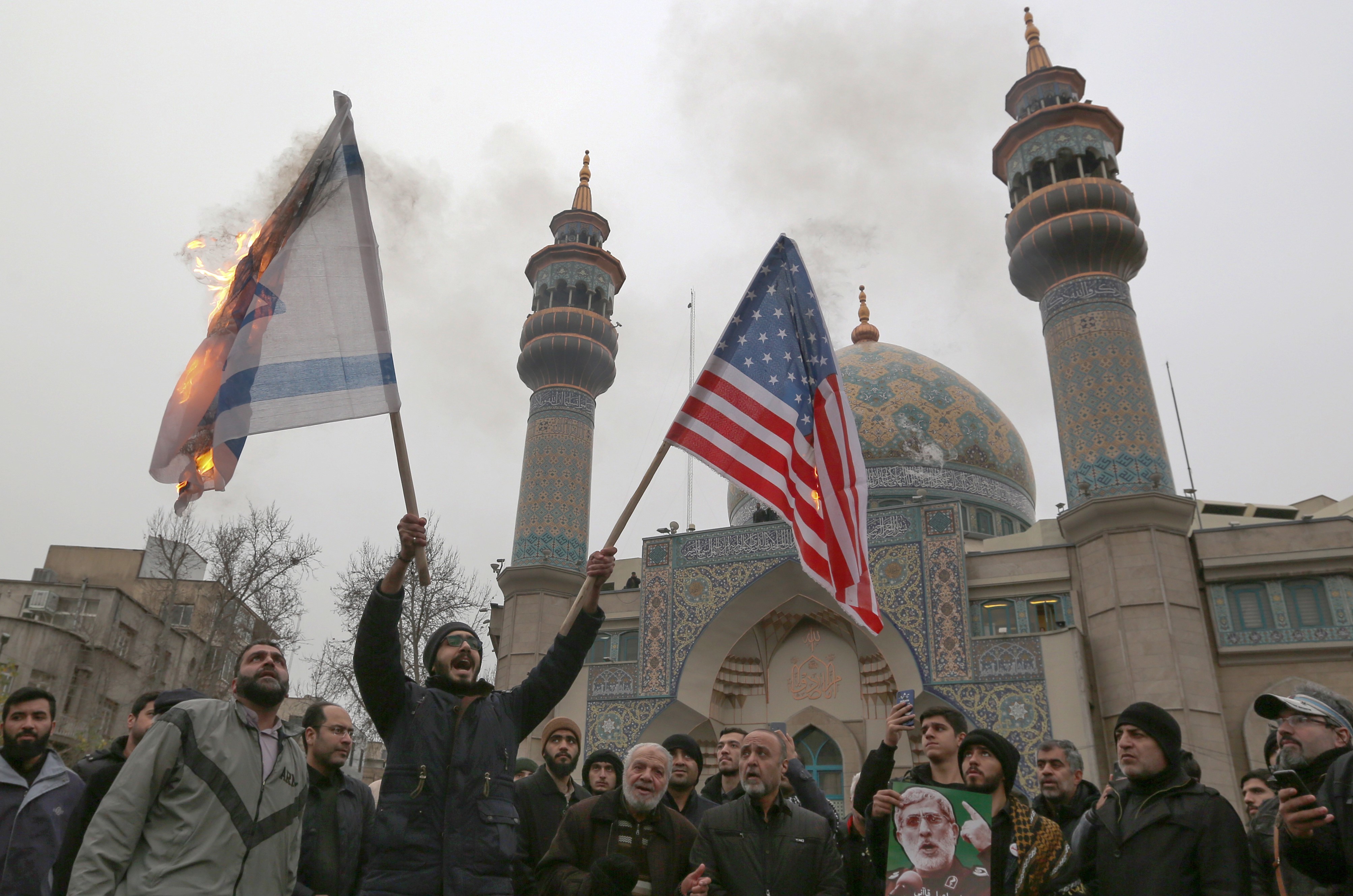 Iranians burn an Israeli and a US flag during an anti-US protest over the killings during a US air stike of Iranian military commander Qasem Soleimani on 4 January (AFP)