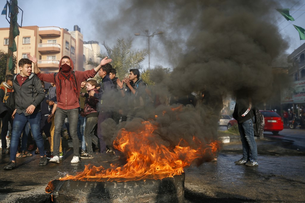 Palestinians shout chants against Trump next to burning tyres in the Gaza Strip (AFP/Mohammed Abed)