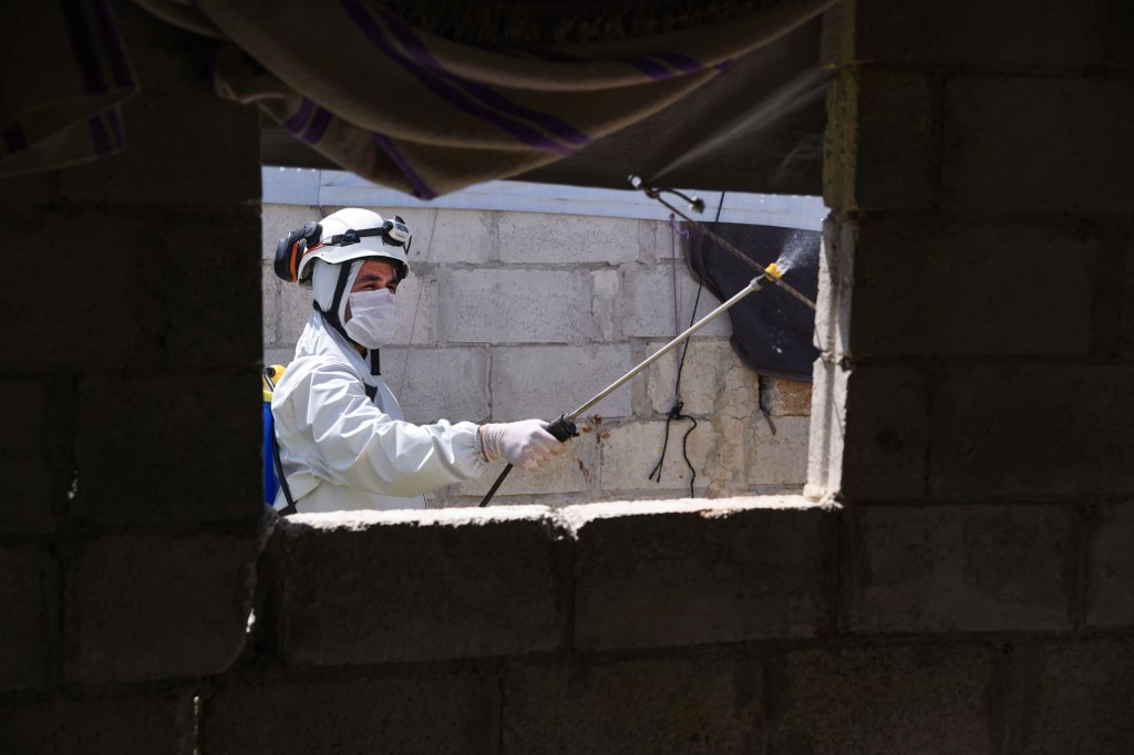 Un membre de la défense civile syrienne désinfecte un bâtiment dans un camp de déplacés de la campagne d’Afrin, dans le nord du gouvernorat d’Alep, le 20 avril 2020 (AFP)