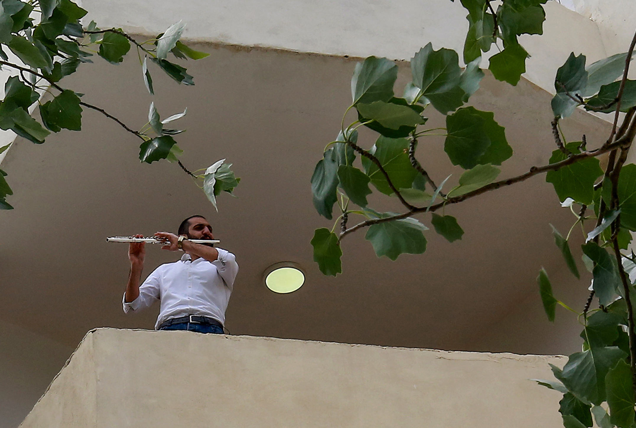 Ebaa Akroush, joue de la flûte sur son balcon dans la ville de Fuheis, au nord-ouest de la capitale Amman, le 27 avril 2020 (AFP)