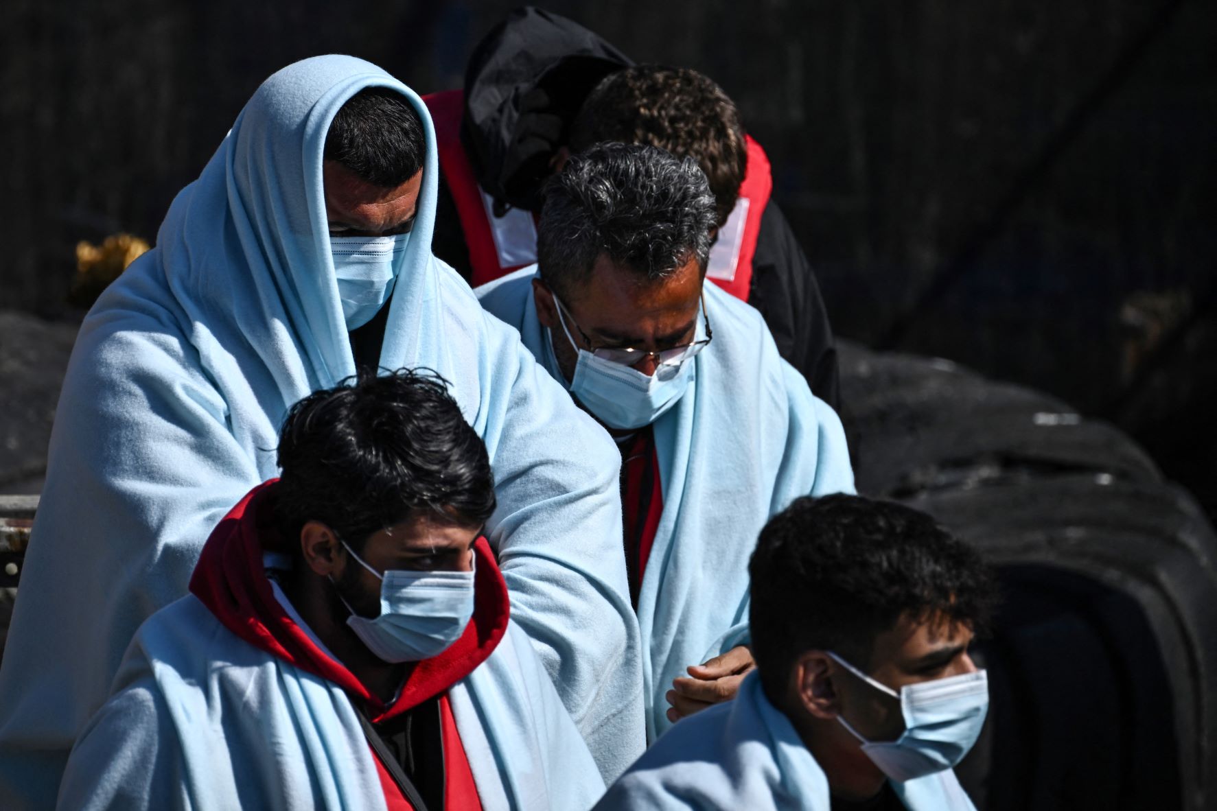 Migrants disembark from a UK Border Force rubber dinghy, after they were picked up at sea while attempting to cross the English Channel, and brought to the Marina in Dover, in June 2022 (AFP)