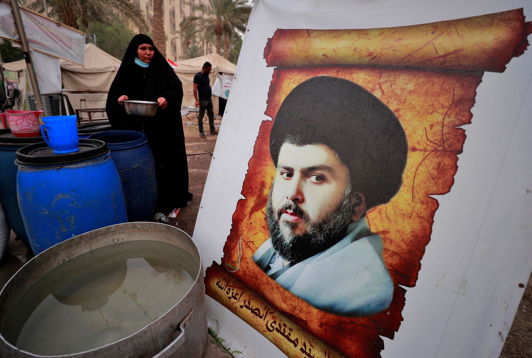 An Iraqi woman carries water for supporters of Iraqi Shia cleric Muqtada al-Sadr (AFP)