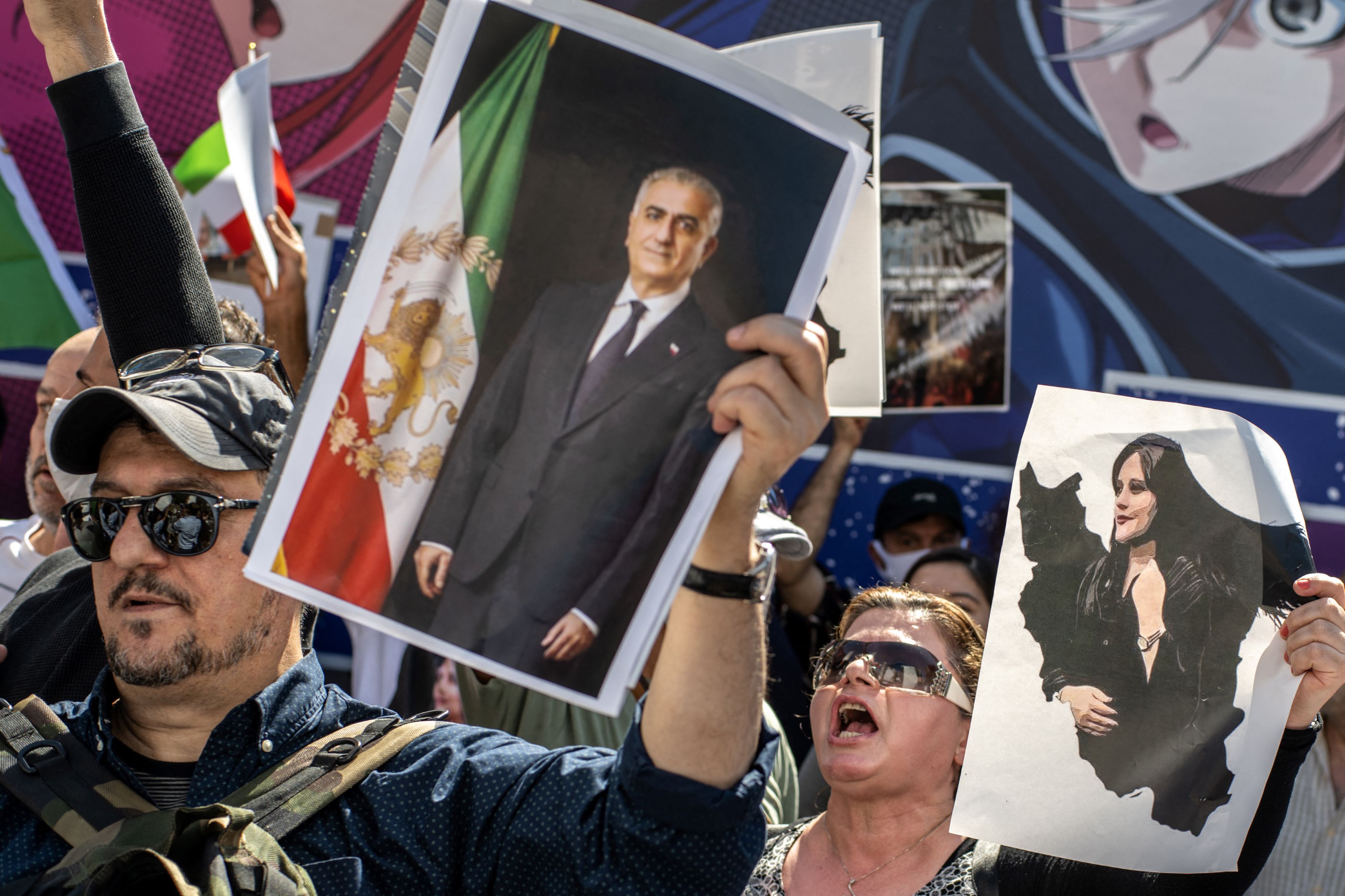 People chant slogans and hold pictures showing Mahsa Amini (R) and Reza Pahlavi (L) during the 