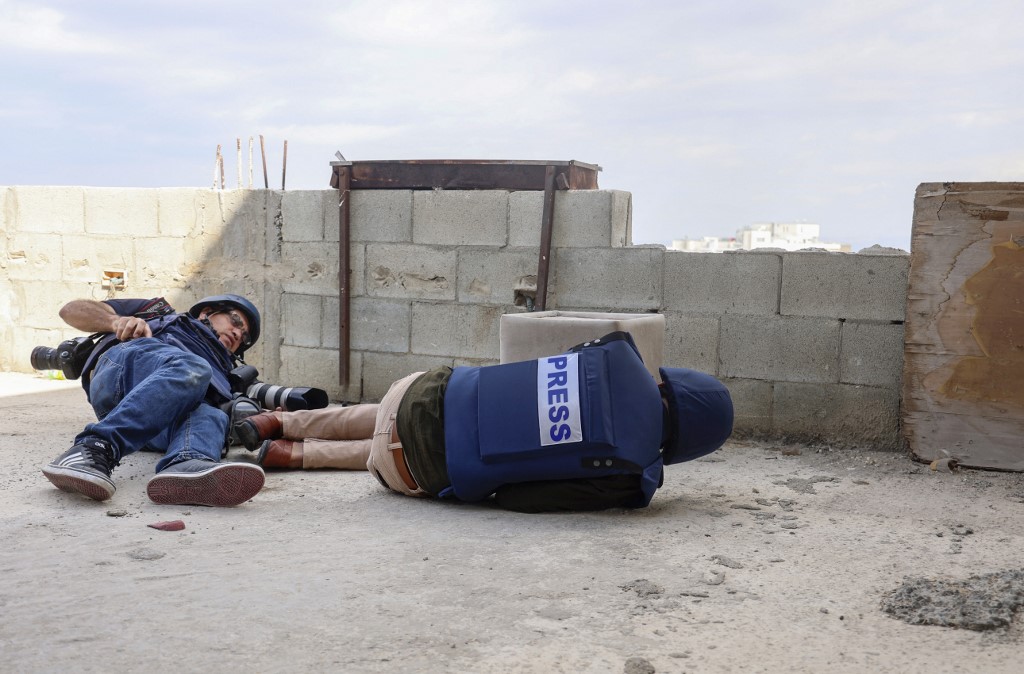 Journalists take cover during an Israeli raid on Jenin in the occupied West Bank on 8 October 2022 (AFP)