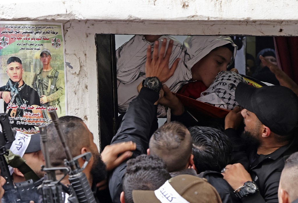 Mourners, including Balata Brigade fighters, carry Mahdi Hashash's body in the refugee camp of Balata near Nablus on 9 November 2022 (AFP)