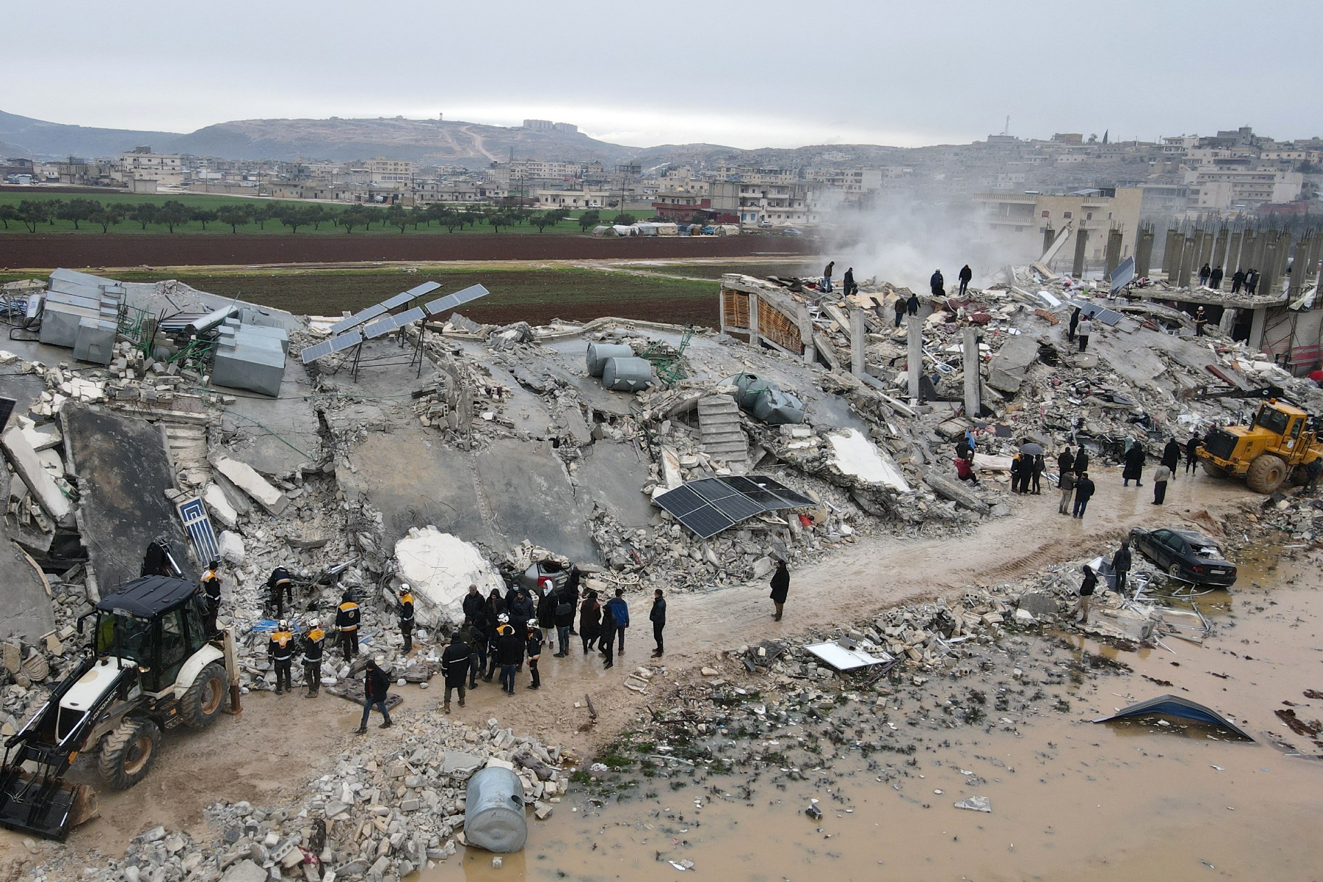 Residents helped by bulldozers searching for victims and survivors in the rubble of collapsed buildings, following an earthquake in the Syrian town of Sarmada (AFP)