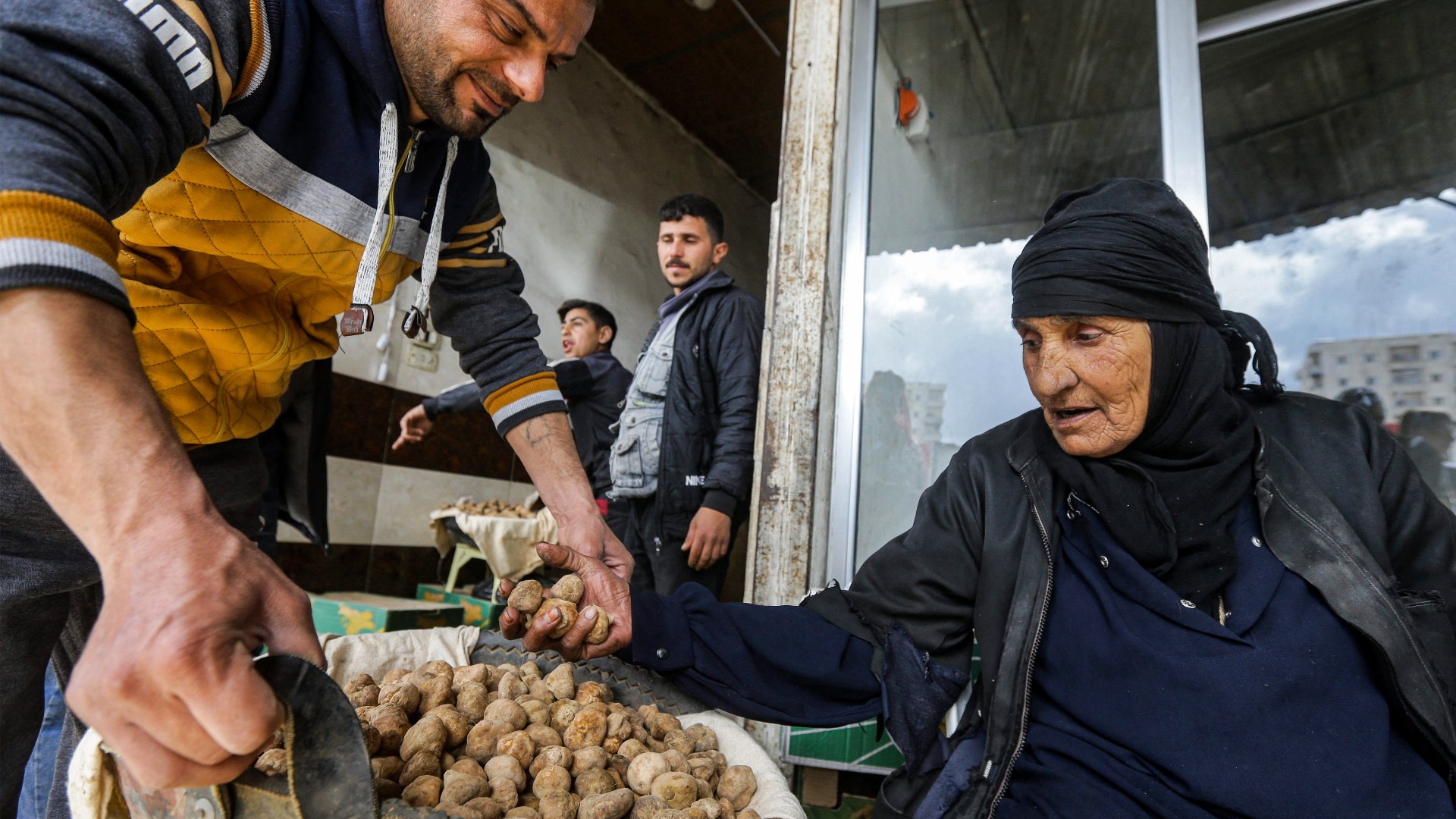 A merchant assists a woman as she sorts through desert truffles at a stall in a market in the city of Hama in west-central Syria on 6 March (AFP)
