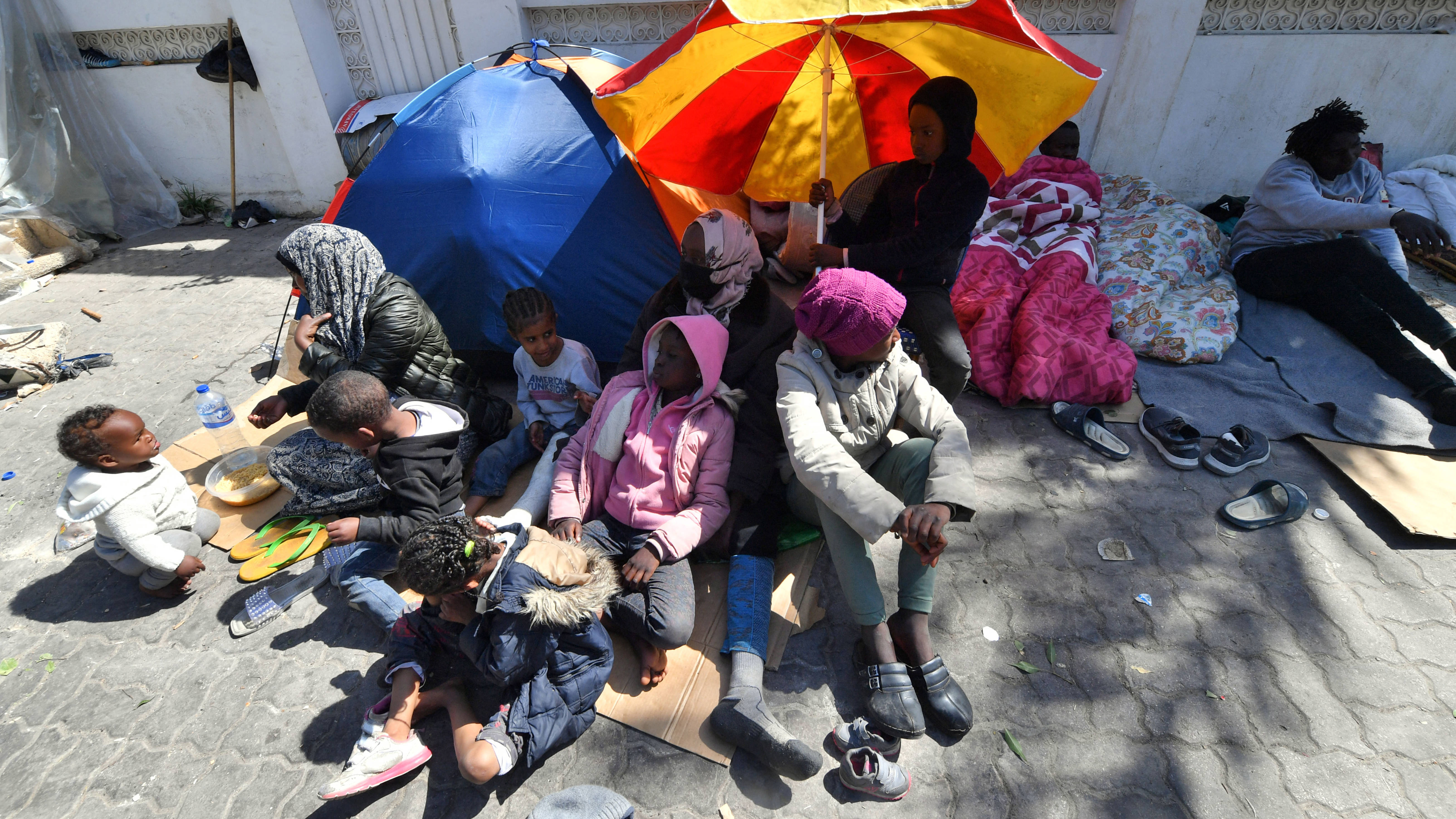 Migrants gather outside the offices of the IOM after Tunisian police dismantled a makeshift camp for refugees in UNHCR headquarters in Tunis, on 12 April 2023 (AFP)