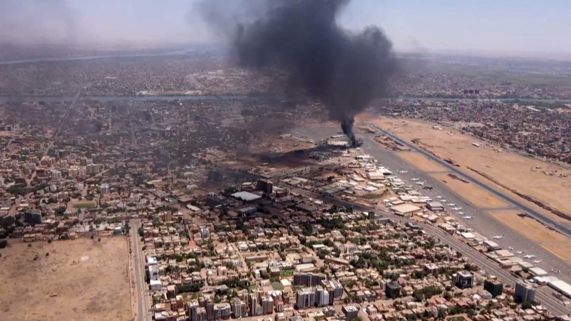 An aerial view of black smoke rising above the Khartoum International Airport on 20 April as fighting engulfed the Sudanese capital (AFP)
