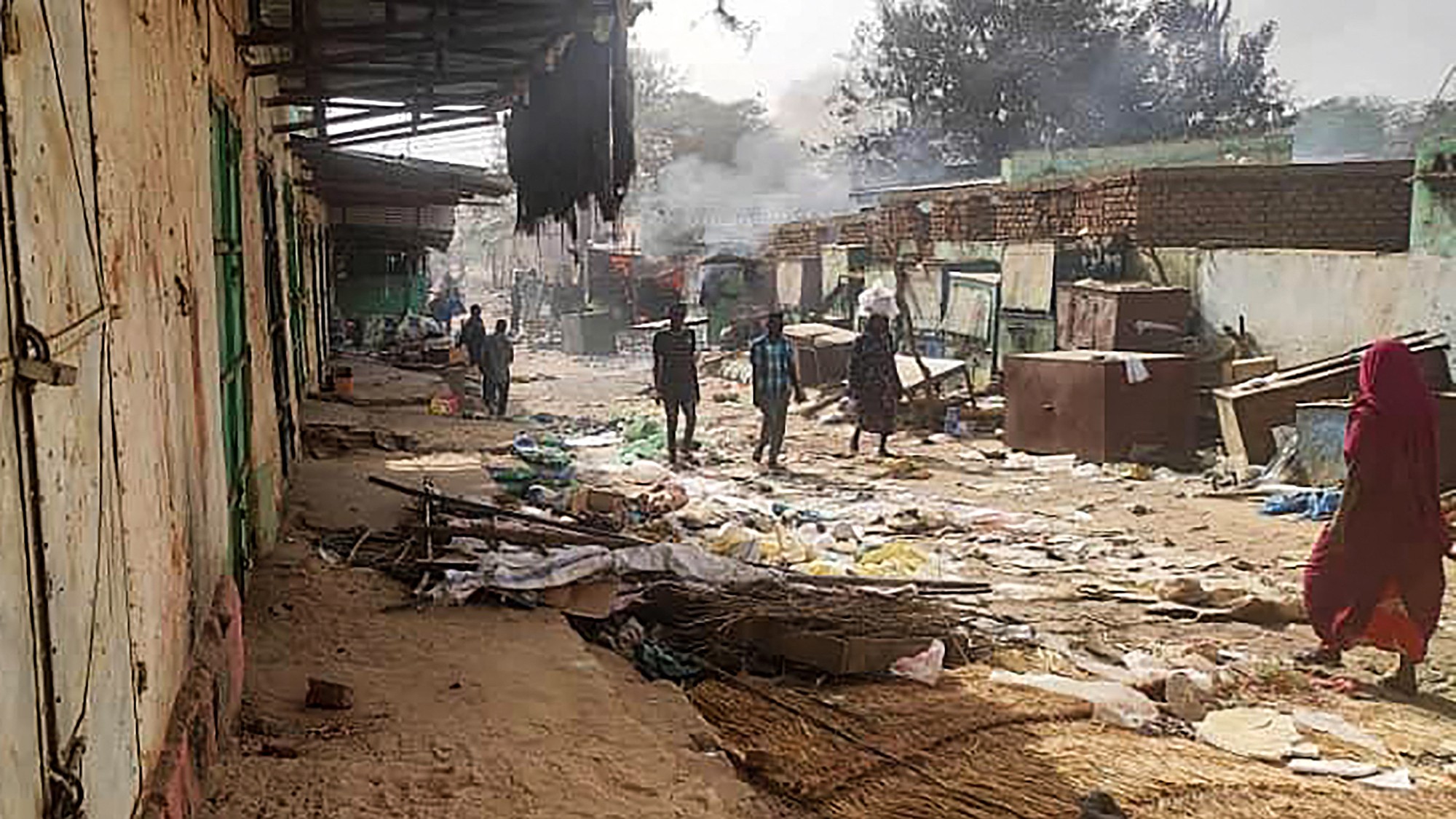 People walk among scattered objects in the market of al-Geneina, the capital of West Darfur, as fighting continues in Sudan on 29 April (AFP)