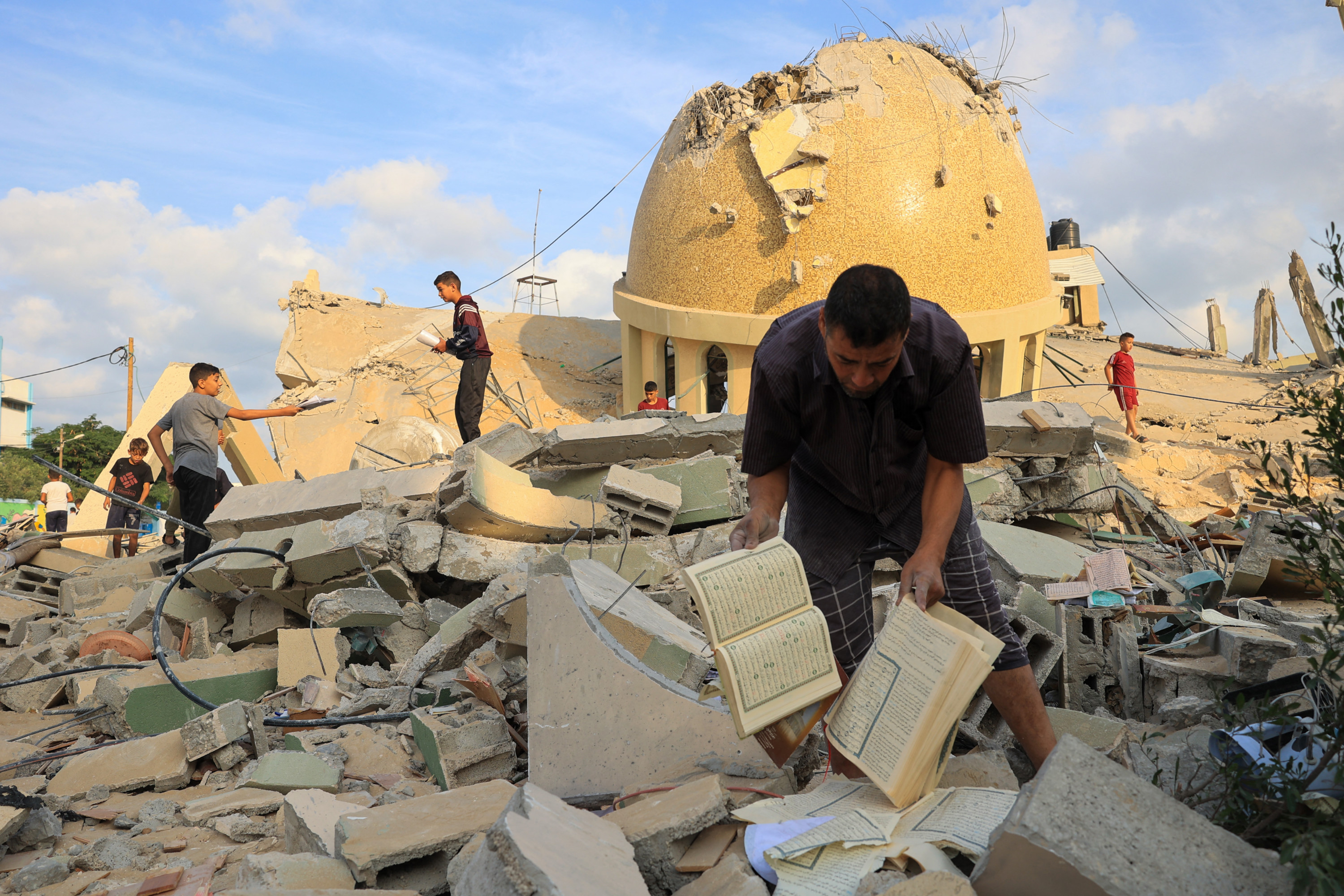 People examine the ruins of a mosque destroyed in Israeli airstrikes in Khan Yunis, southern Gaza Strip, on 8 October 2023 (AFP)