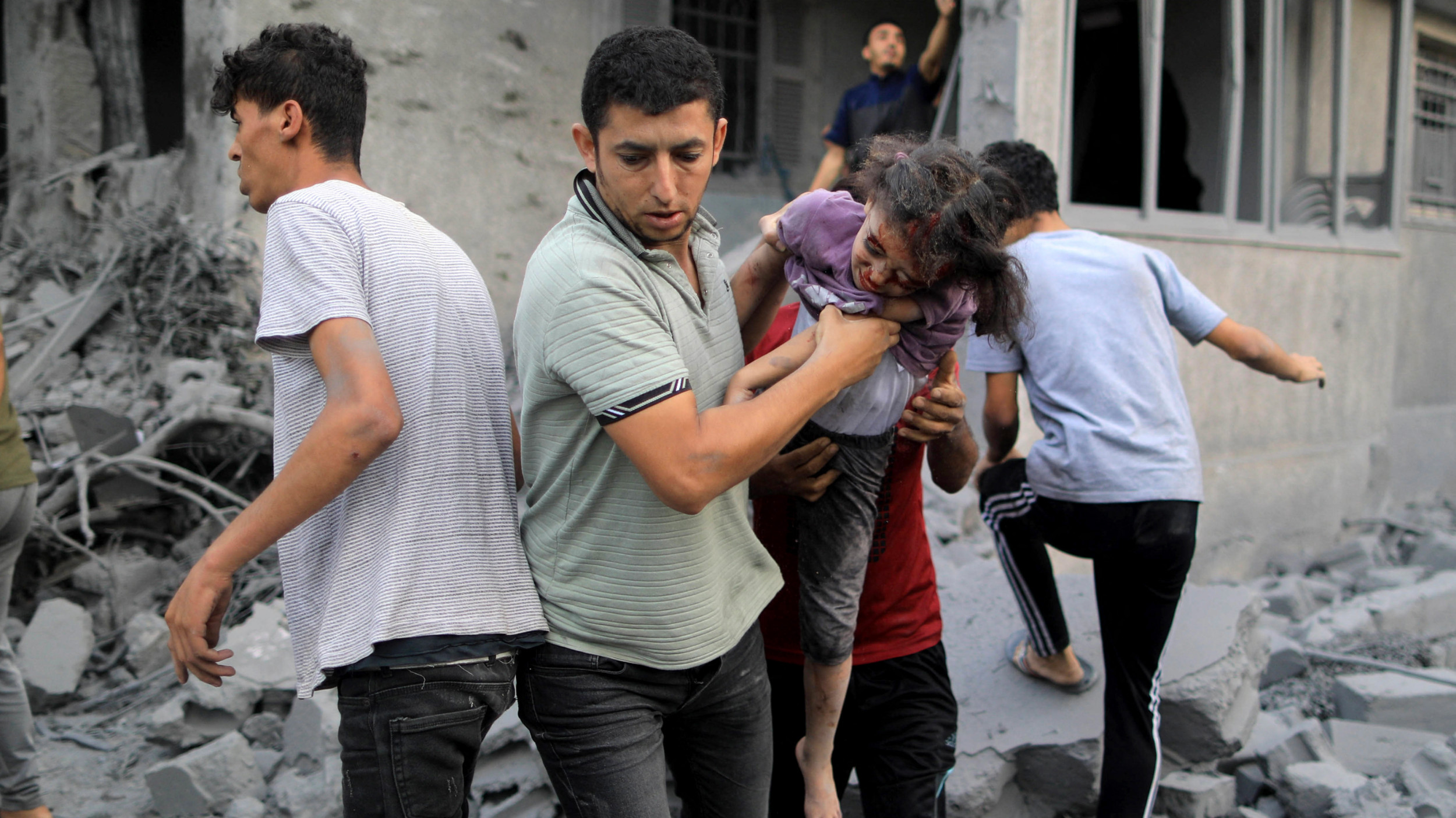 A Palestinian man rescues a girl from the rubble of a building following an Israeli strike, in Khan Yunis in the southern Gaza Strip on October 14, 2023