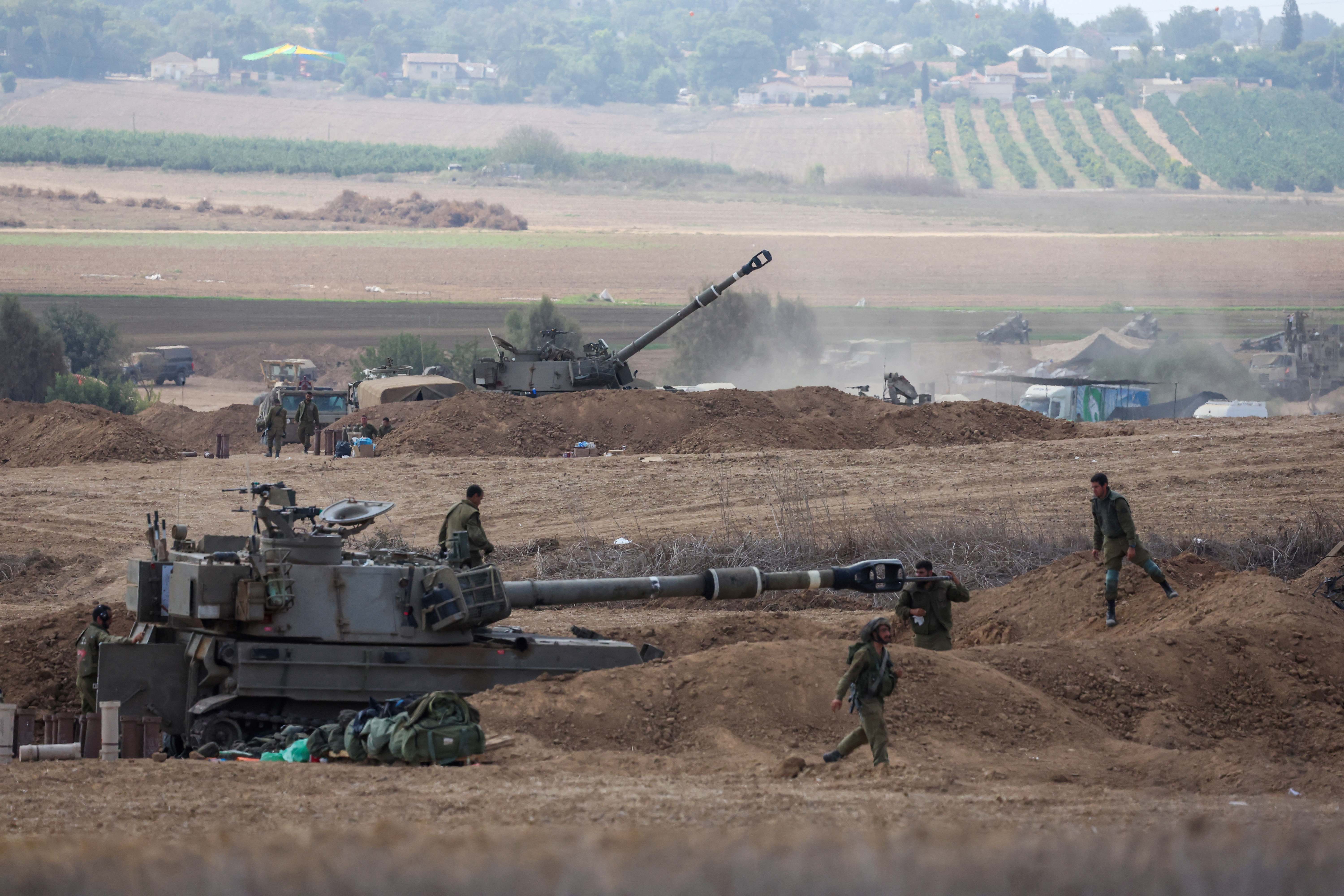 Israeli soldiers clean the barrel of a self-propelled howitzer in southern Israel bordering Gaza on 13 October