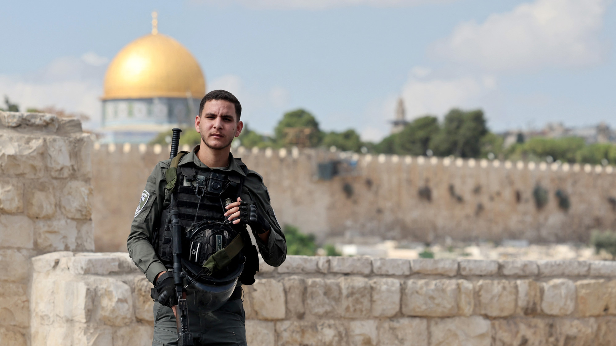 An Israeli soldier watches Palestinians perform Friday prayers in occupied East Jerusalem on 20 October 2023 after they were banned from reaching Al-Aqsa Mosque (AFP/Ahmad Gharabli)