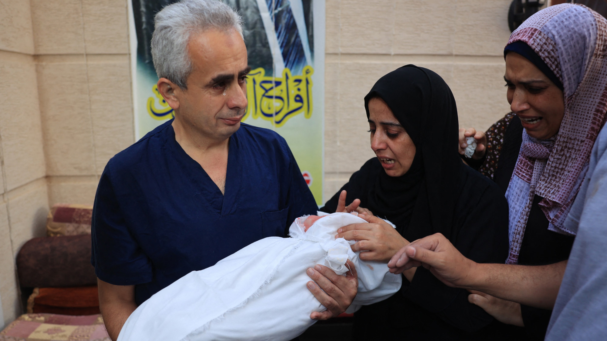 Palestinian man carries the body of his 8-month-old child Ahmed during a funeral for his wife and four of his children killed in Israeli bombardment, in Rafah on 6 November 2023 (AFP) 