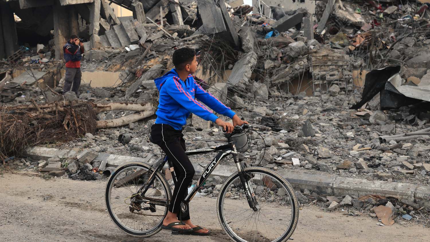 A Palestinian boy on a bicycle looks at rubble of a building following Israeli strikes in Rafah in the southern Gaza Strip on 22 November 2023.