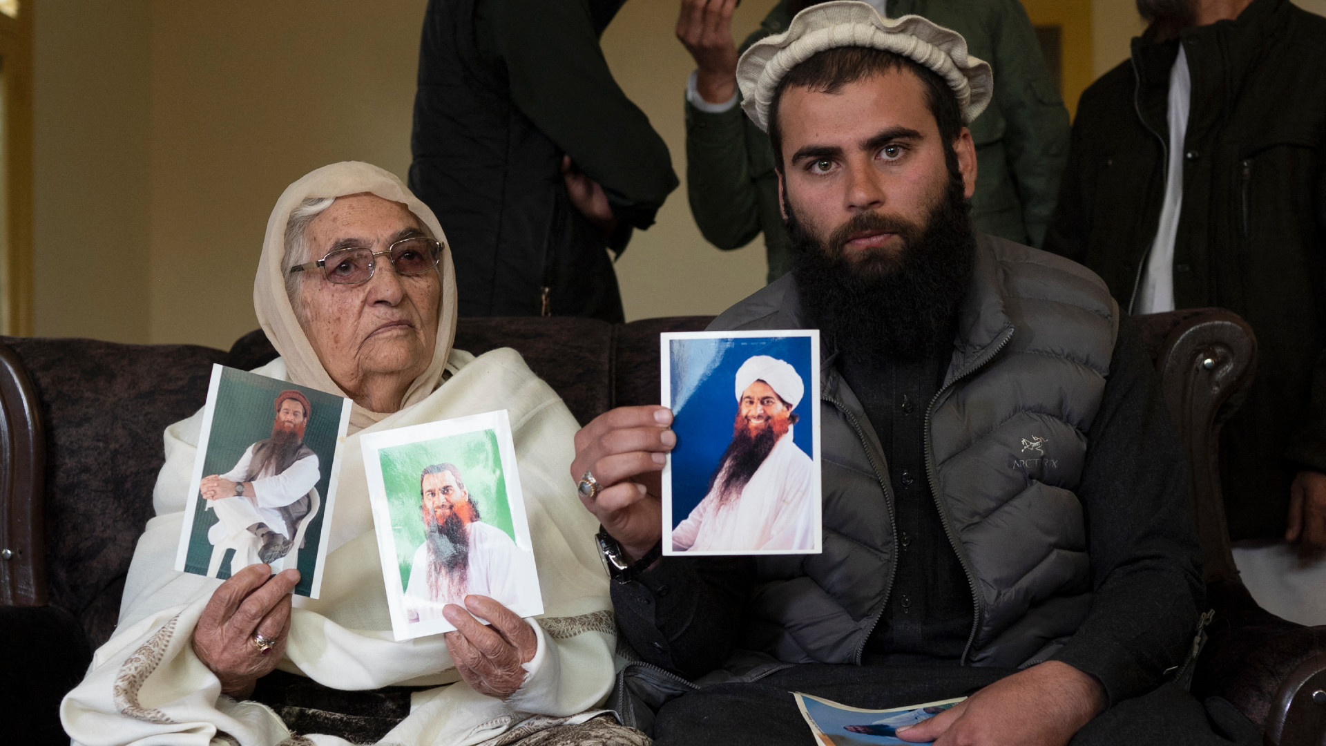 Safoora Bibi, mother of Muhammad Rahim (L) with Muhammad Ismail, son of Muhammad Rahim display pictures of Muhammad Rahim who is one of the last Afghans held at the Guantanamo Bay US detention centre in Cuba, as the family calls for his release during a news conference held at her home in Kabul, Afghanistan, on 29 November 2023 (Wakil Kohsar/AFP)