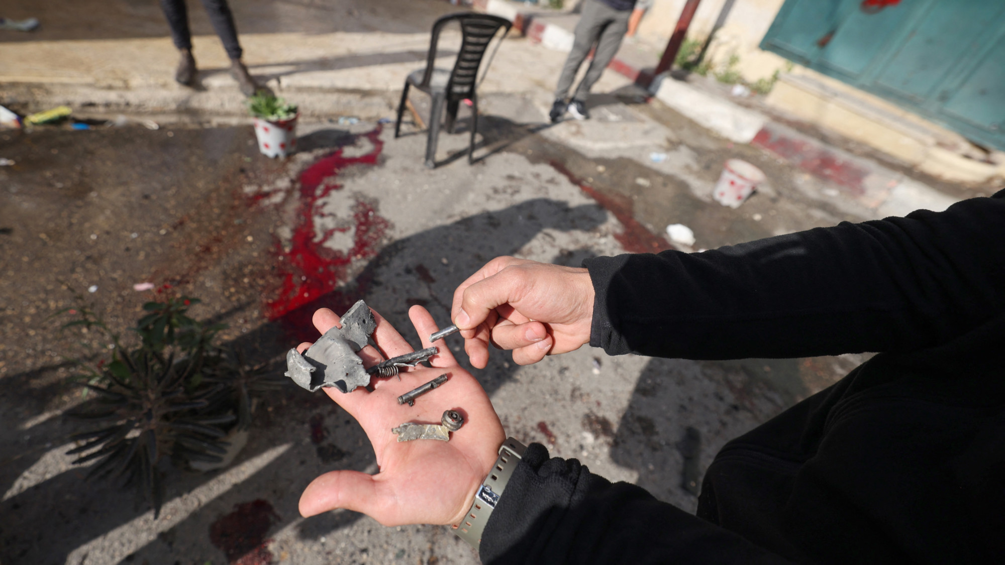 People inspect the site where four Palestinians were reportedly killed in an Israeli drone strike in the Jenin refugee camp in the occupied West Bank during a raid on 12 December 2023 (AFP)