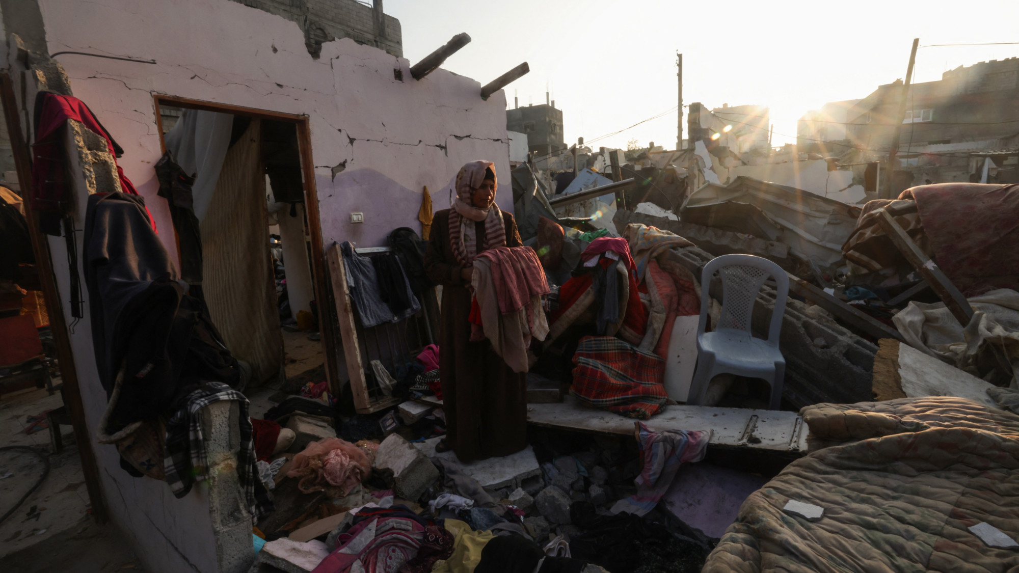 Palestinian woman standing amid rubble and belongings in Rafah in the southern Gaza Strip 1 January 2024 (AFP)
