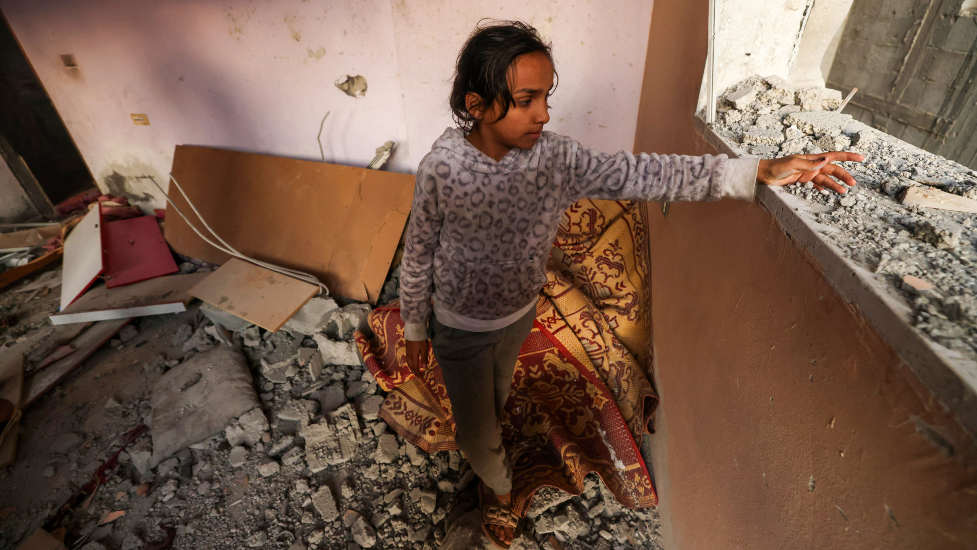 A girl reacts standing in a house destroyed by Israeli bombardment in Rafah refugee camp, south of the Gaza Strip, on 1 January 2024 (AFP)