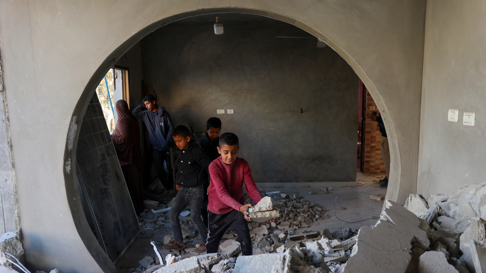 A child sifts through the rubble of the destroyed home in Khan Younis (Said Khatib/Reuters)