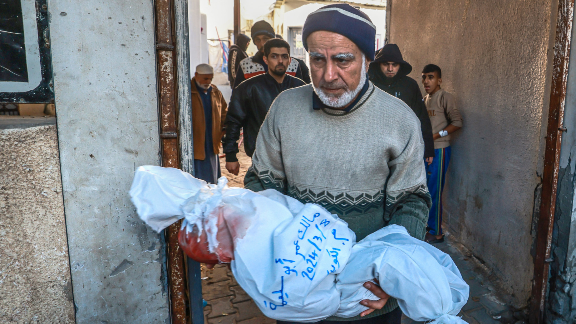A Palestinian man carries the body of a child of the Abu Slemah family at al-Najar hospital in Rafah in the southern Gaza Strip on 8 March 2024 (Mohammed Abde/AFP)