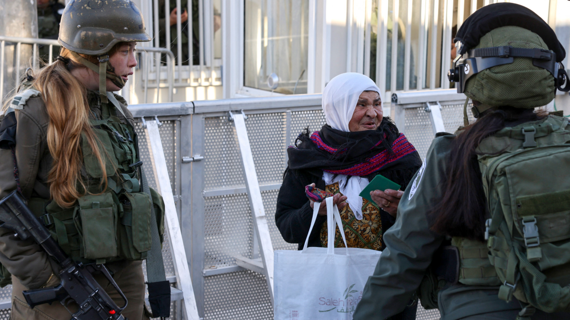 Israeli soldiers check Palestinians crossing a checkpoint in Bethlehem, in the occupied West Bank, on 22 March 2024 (Hazem Bader/AFP)
