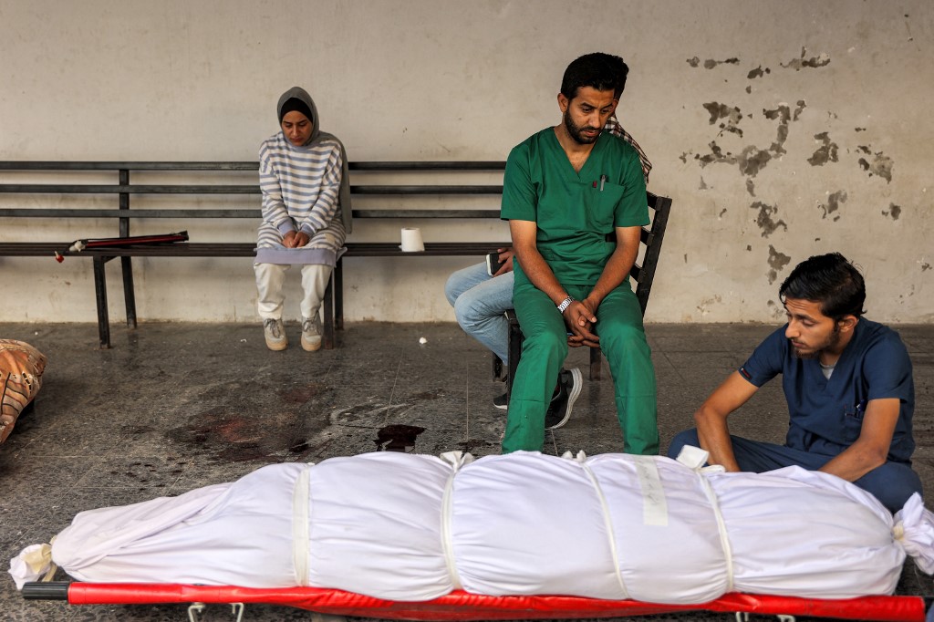 Medical staffers at the Ahli Arab Hospital mourn by the shrouded body of their colleague, a nurse who was killed during Israeli bombardment the previous night at the Shati refugee camp, at the hospital premises in Gaza City on June 14, 2024