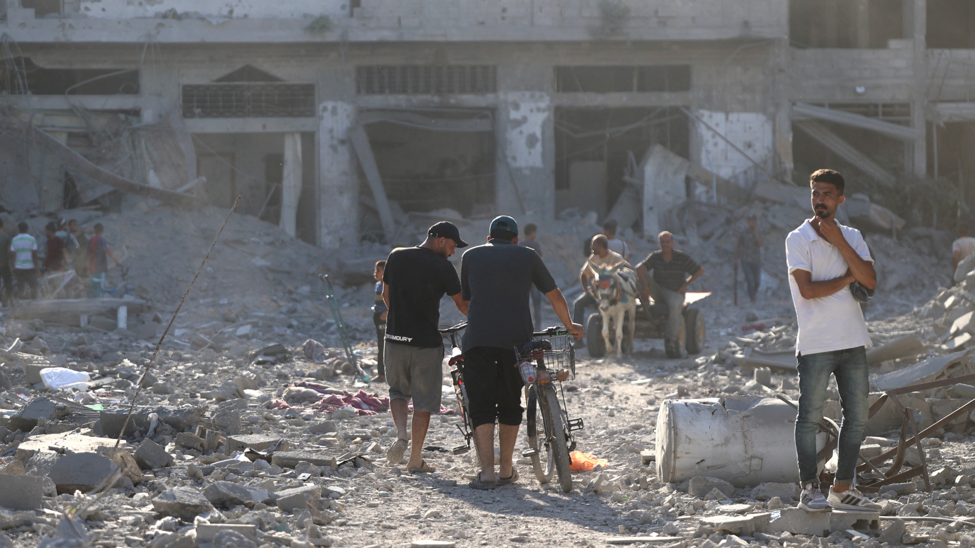 A Palestinian stands on a breeze block looking at the destroyed buildings after the Israeli military withdrew from the Shujaiya neighbourhood, east of Gaza City on 10 July 2024 (AFP/Omar al-Qattaa)