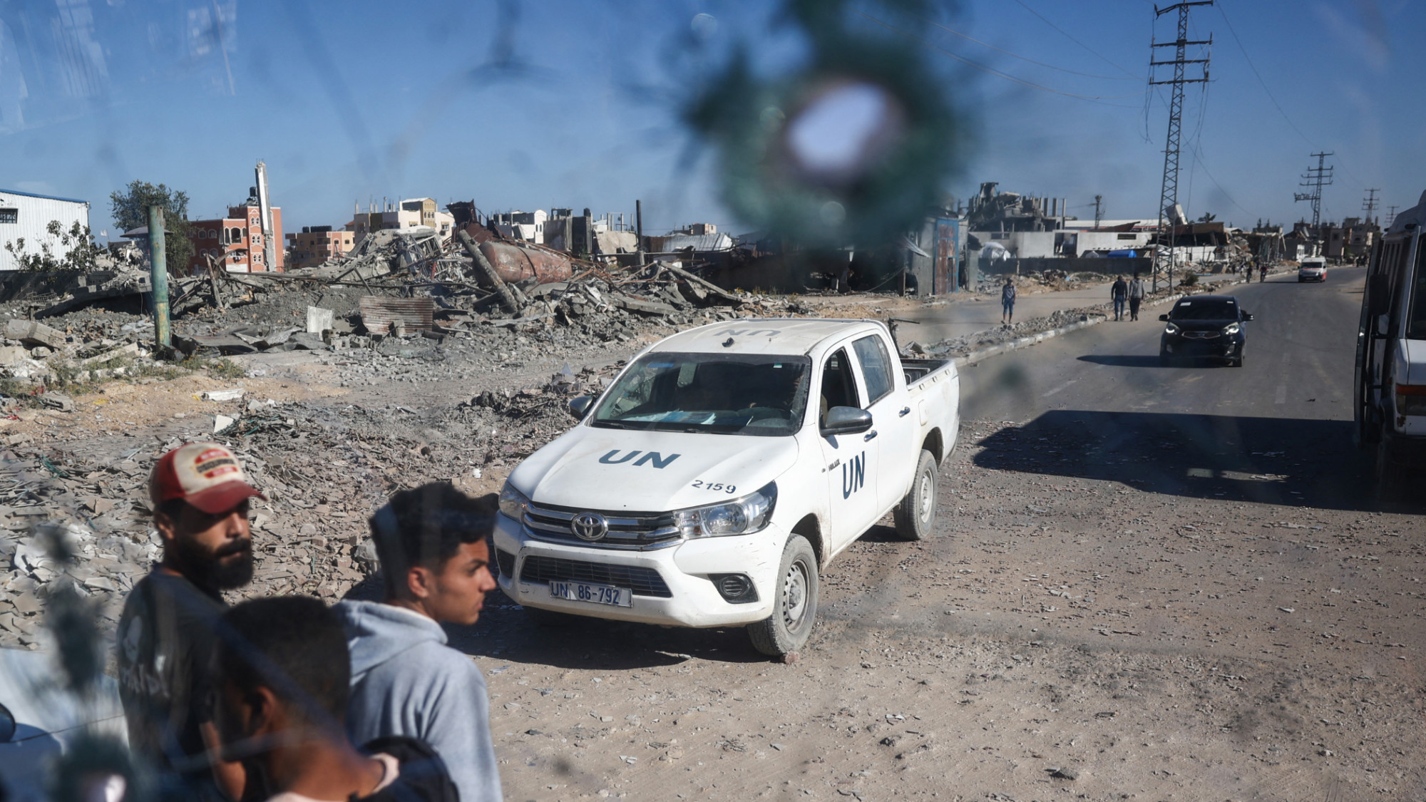 A UN vehicle is seen through the shrapnel-riddled windscreen of a bus that was damaged from Israeli shelling outside Deir el-Balah in the central Gaza Strip, on 24 October 2024 (AFP/Eyad Baba)