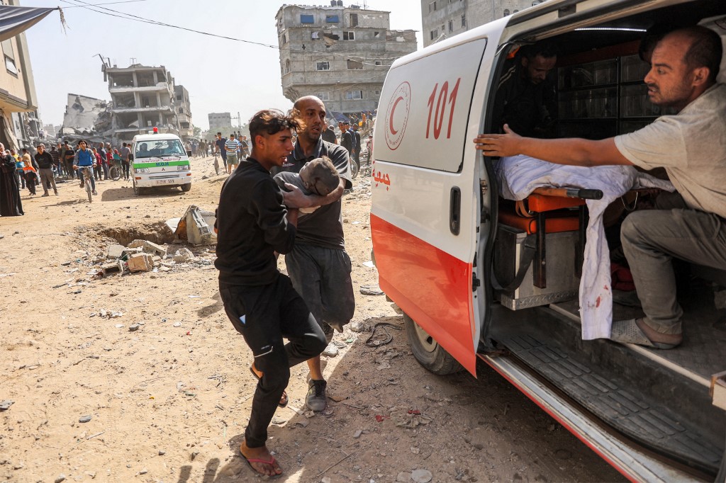 Men bring to an ambulance the body of a child victim rescued from the rubble following Israeli bombardment on the north of Gaza City on October 26, 2024. (Omar AL-Qattaa / AFP)