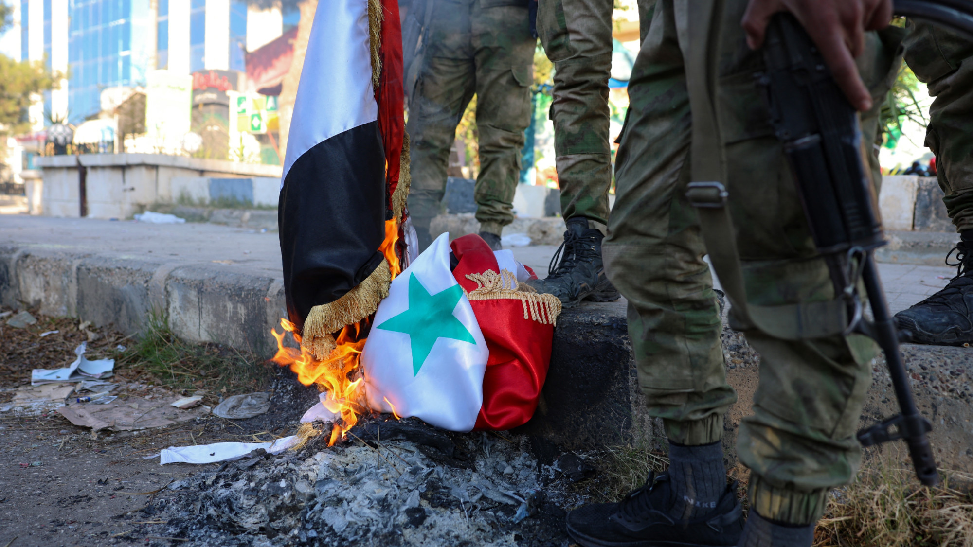 Anti-government fighters burn a Syrian national flag in Aleppo, after rebels and their allies entered the northern Syrian city, on 30 November 2024 (AFP/Mohammed al-Rifai)